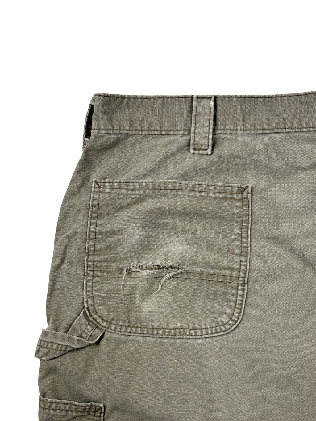 Nahaufnahme der hinteren linken Gesäßtasche der Carhartt Shorts mit einem markanten, horizontalen Riss (Thrashed-Detail) im ausgewaschenen Canvas-Stoff.