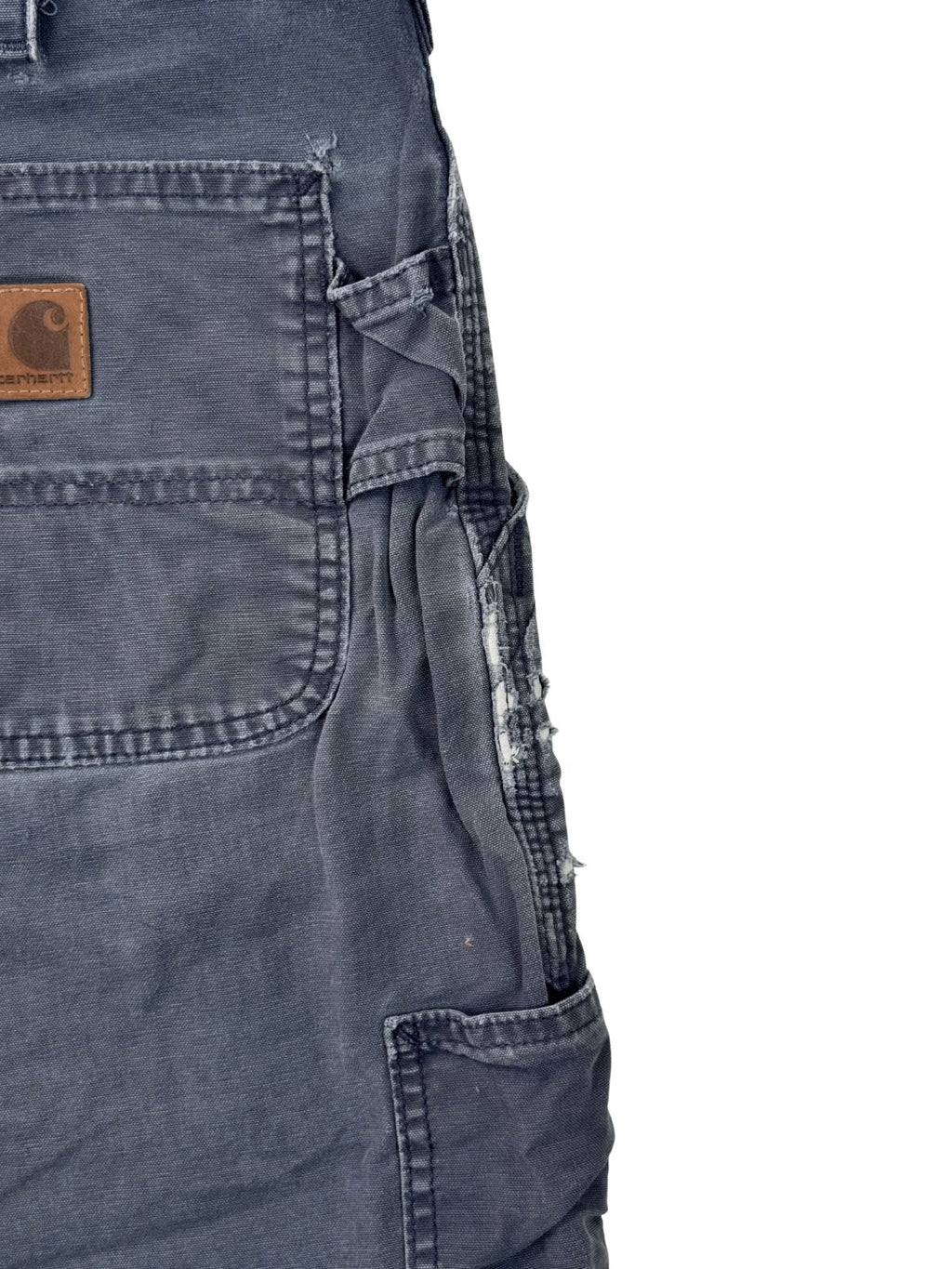 Detailansicht der seitlichen Tool-Pocket einer Carhartt Carpenter Shorts mit starken Ausfransungen und authentischem Thrashed-Effekt.