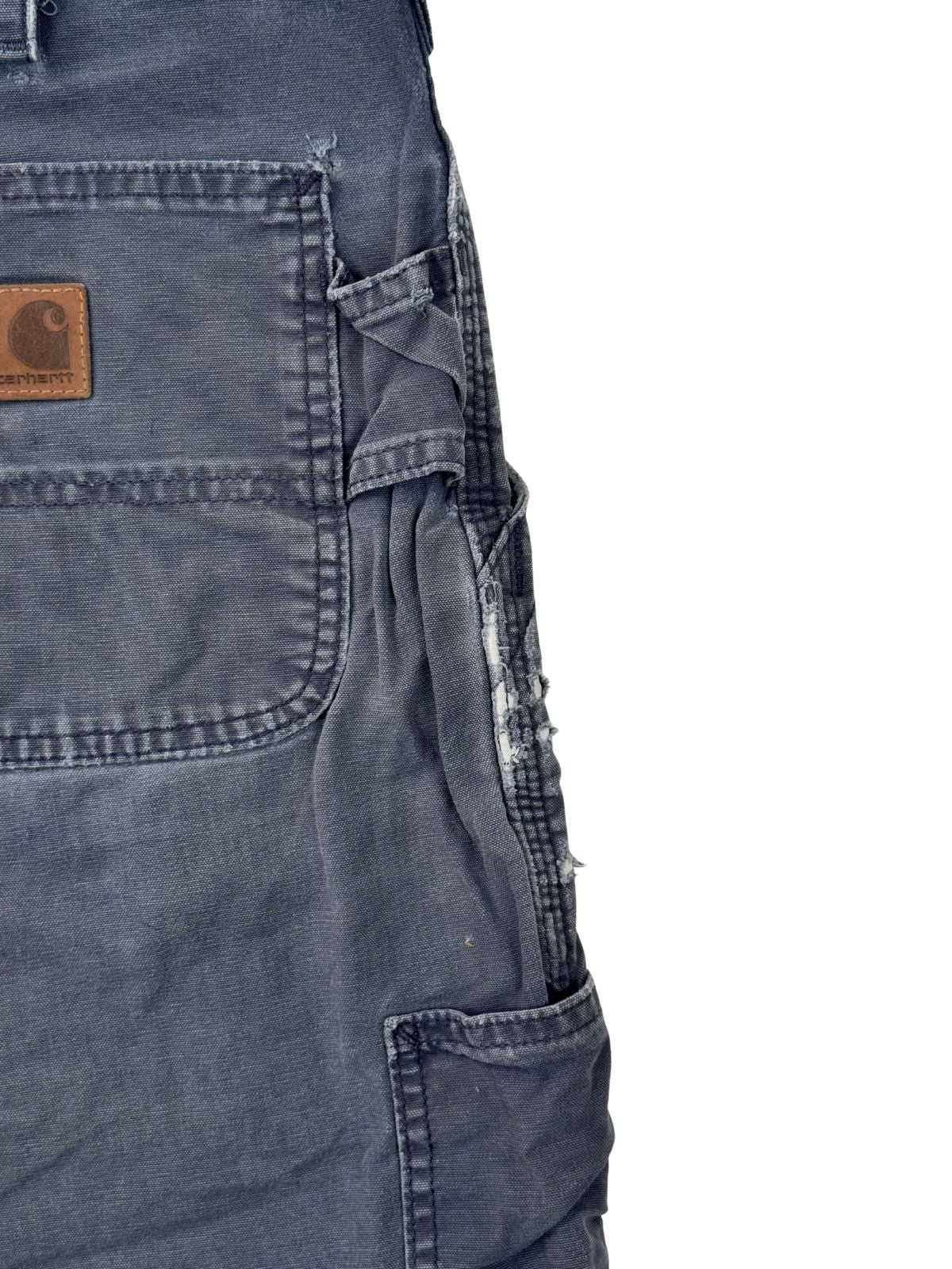 Detailansicht der seitlichen Tool-Pocket einer Carhartt Carpenter Shorts mit starken Ausfransungen und authentischem Thrashed-Effekt.