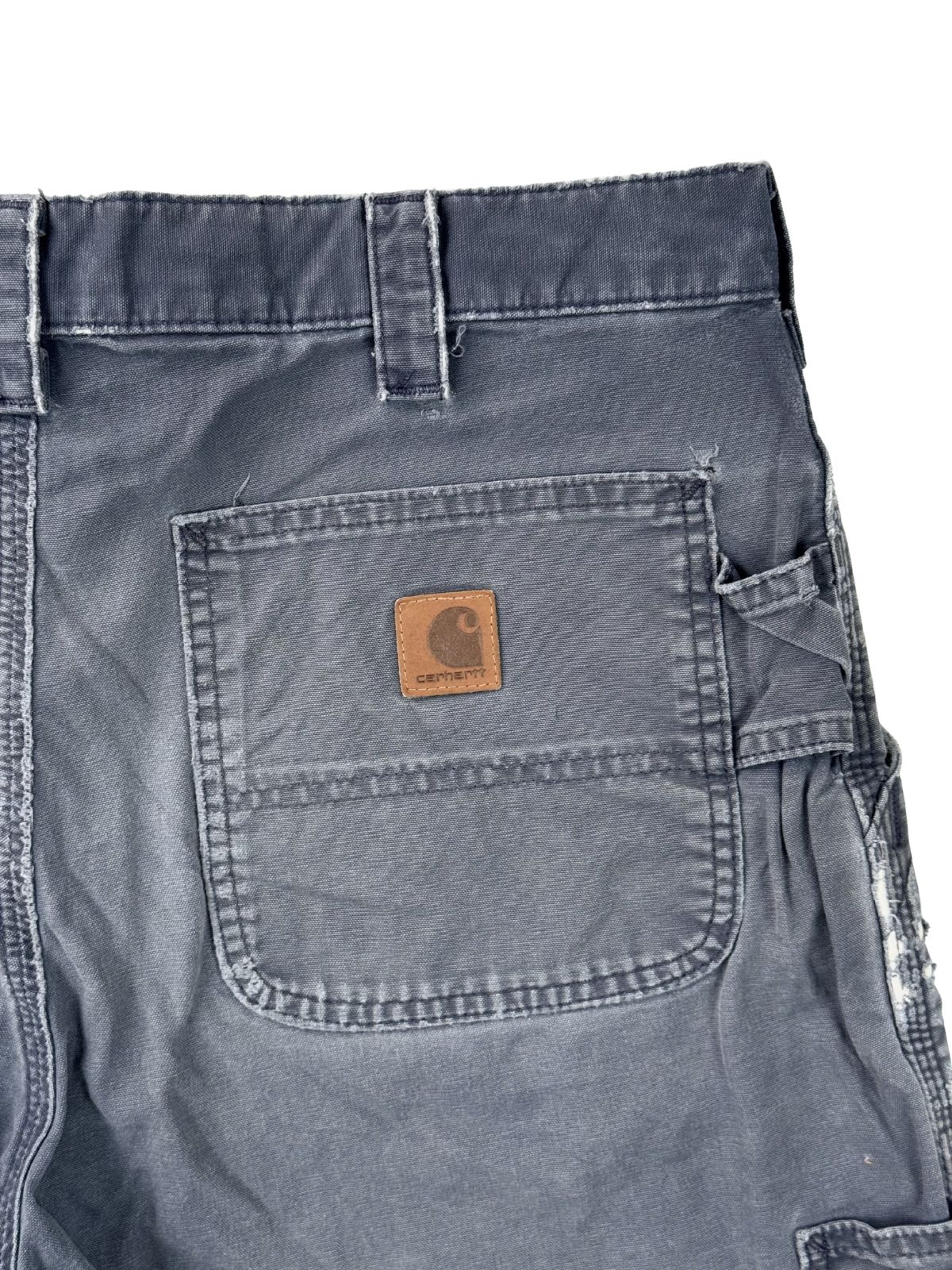 Detailaufnahme der Gesäßtasche einer Vintage Carhartt Shorts mit dem klassischen quadratischen Leder-Logo und sichtbarer Canvas-Struktur.