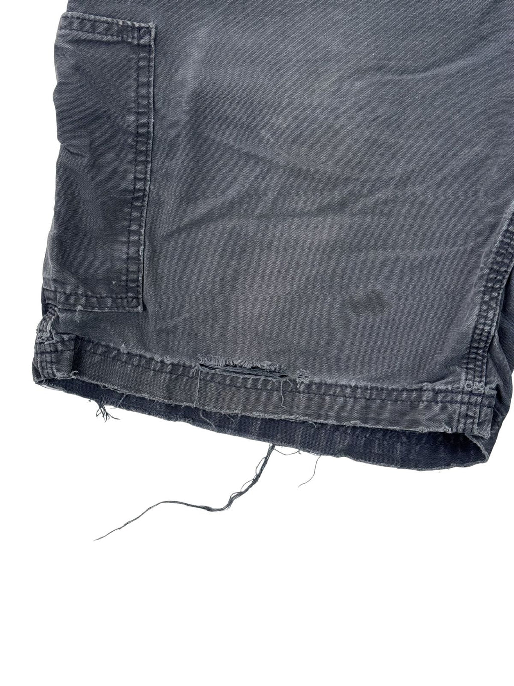 Detailaufnahme des Hosenbeins mit Fransen und dezenten Flecken auf dem dunkelblauen Stoff.
