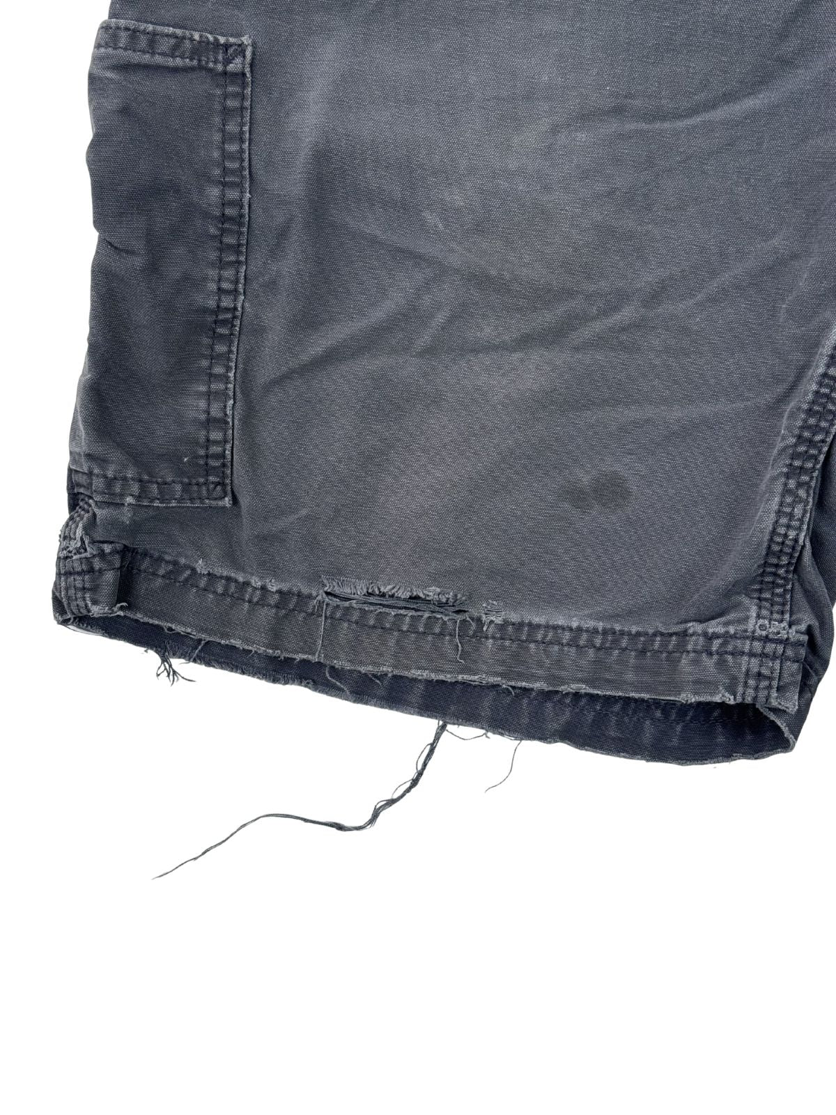 Detailaufnahme des Hosenbeins mit Fransen und dezenten Flecken auf dem dunkelblauen Stoff.