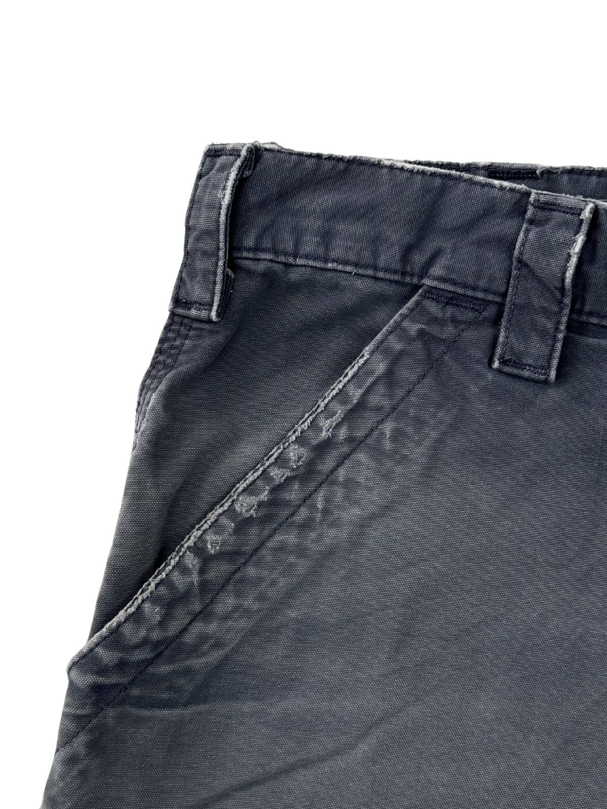 Nahaufnahme der rechten Vordertasche einer verwaschenen blauen Carhartt Shorts mit Distressed-Kanten an den Saumnähten.
