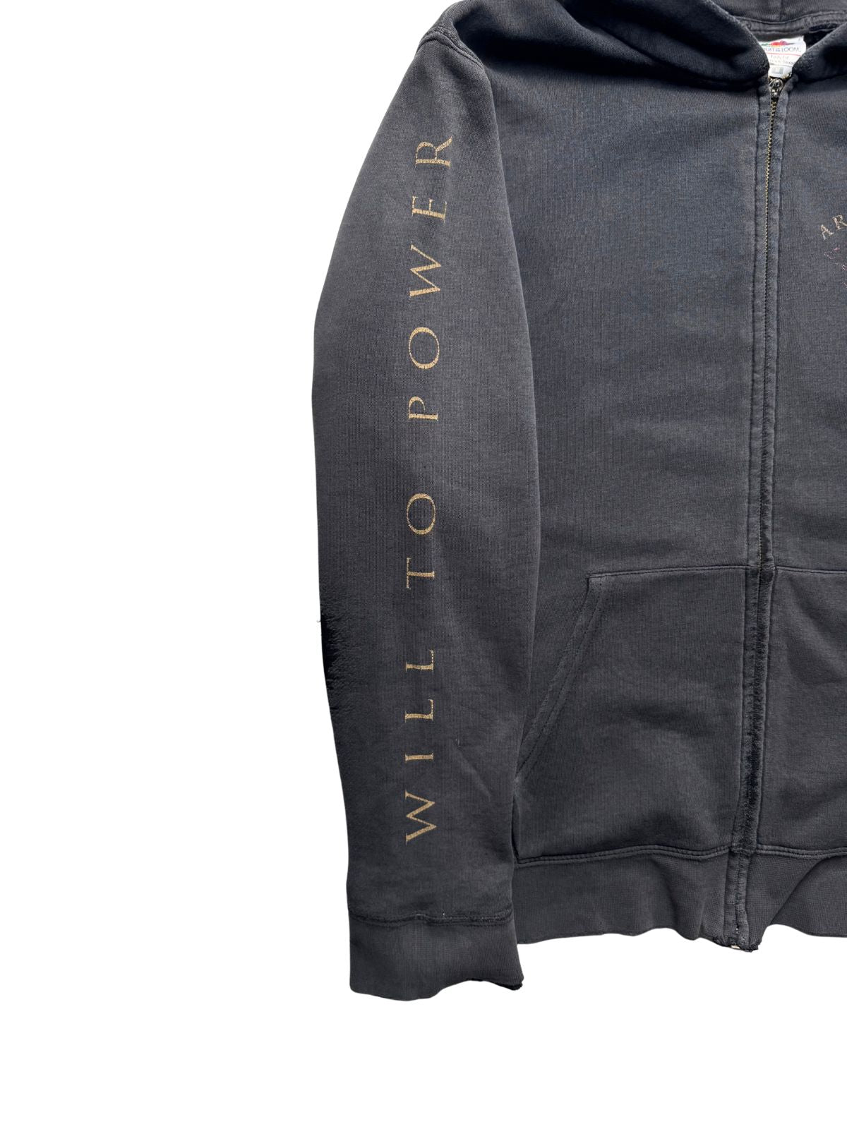 Nahaufnahme des rechten Ärmels mit dem verblassten goldfarbenen Aufdruck „WILL TO POWER“ auf verwaschenem schwarzem Sweatshirt-Stoff.