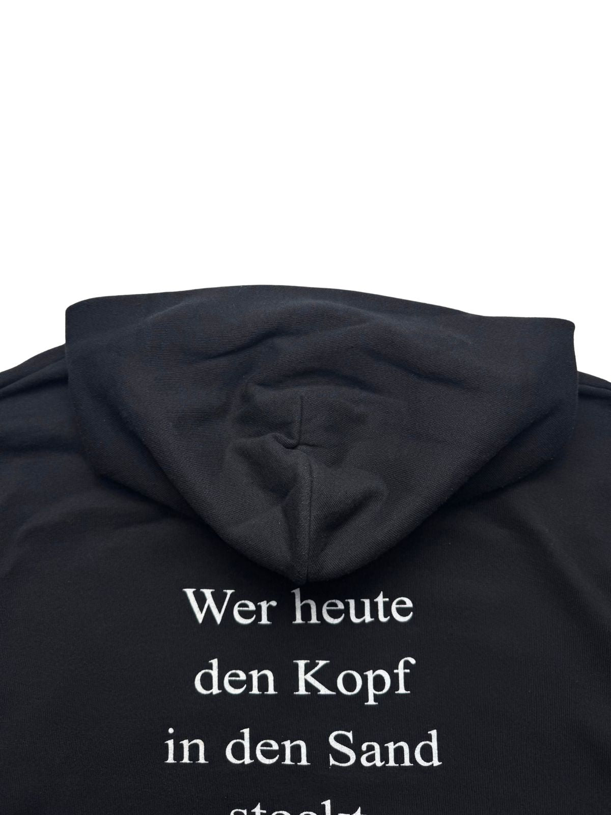 Detailansicht der Kapuze von hinten auf dem schwarzen Baumwoll-Sweatshirt-Stoff oberhalb des Rückendrucks.