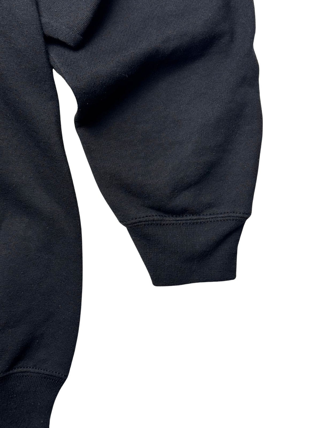 Detailansicht des Ärmels mit geripptem Bündchen auf dichtem schwarzen Sweatshirt-Material.