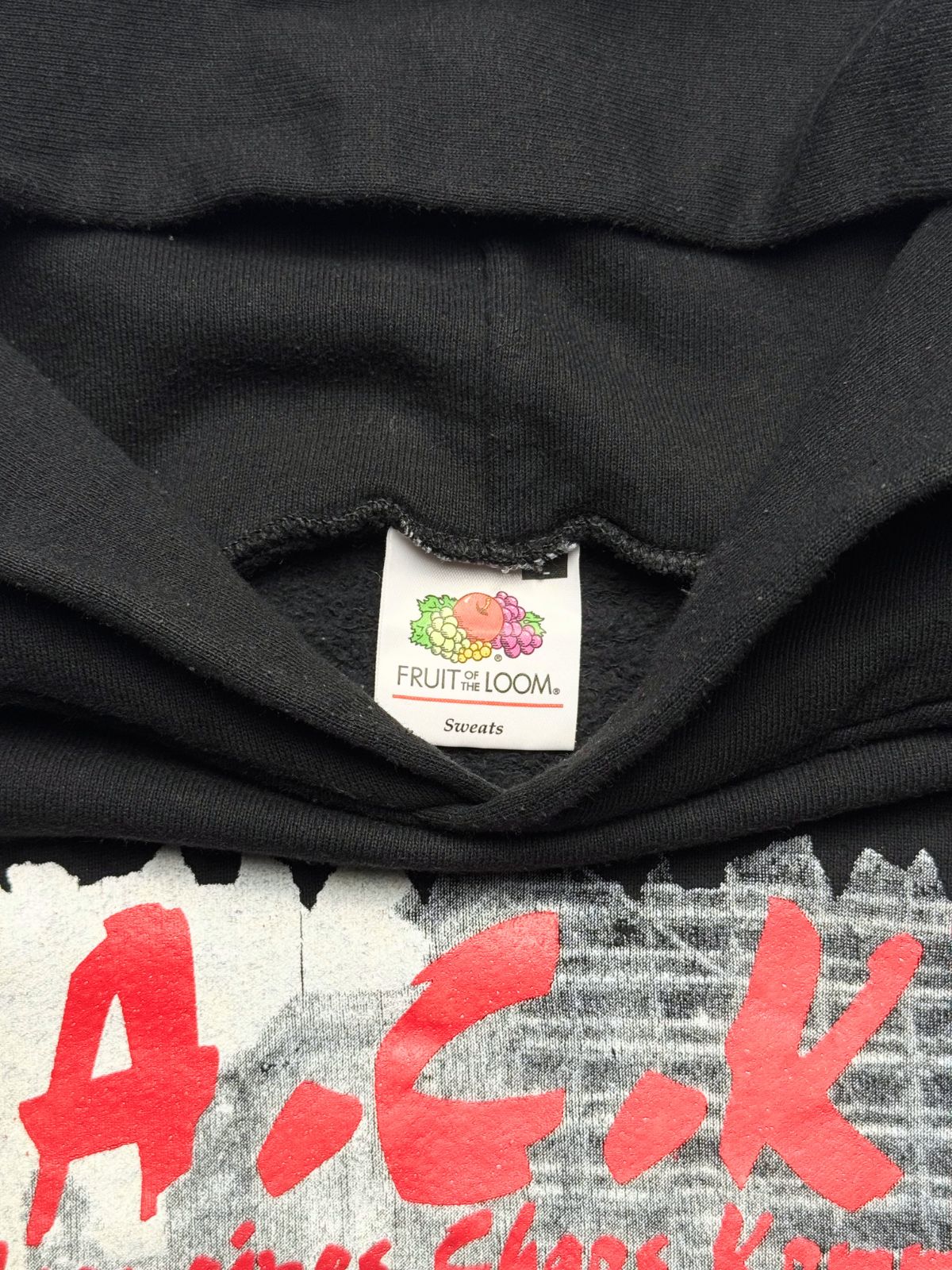 Makroaufnahme des Kragenbereichs mit dem originalen „Fruit of the Loom Sweats“-Nackenetikett oberhalb des vorderen Siebdrucks.