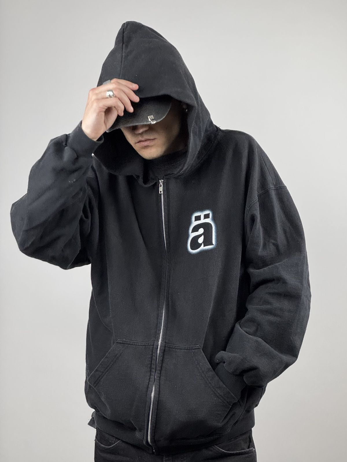 Person trägt den schwarzen Die Ärzte Kapuzenpulli mit Reißverschluss; Fokus auf der lockeren Vintage-Passform und dem markanten Brustprint.