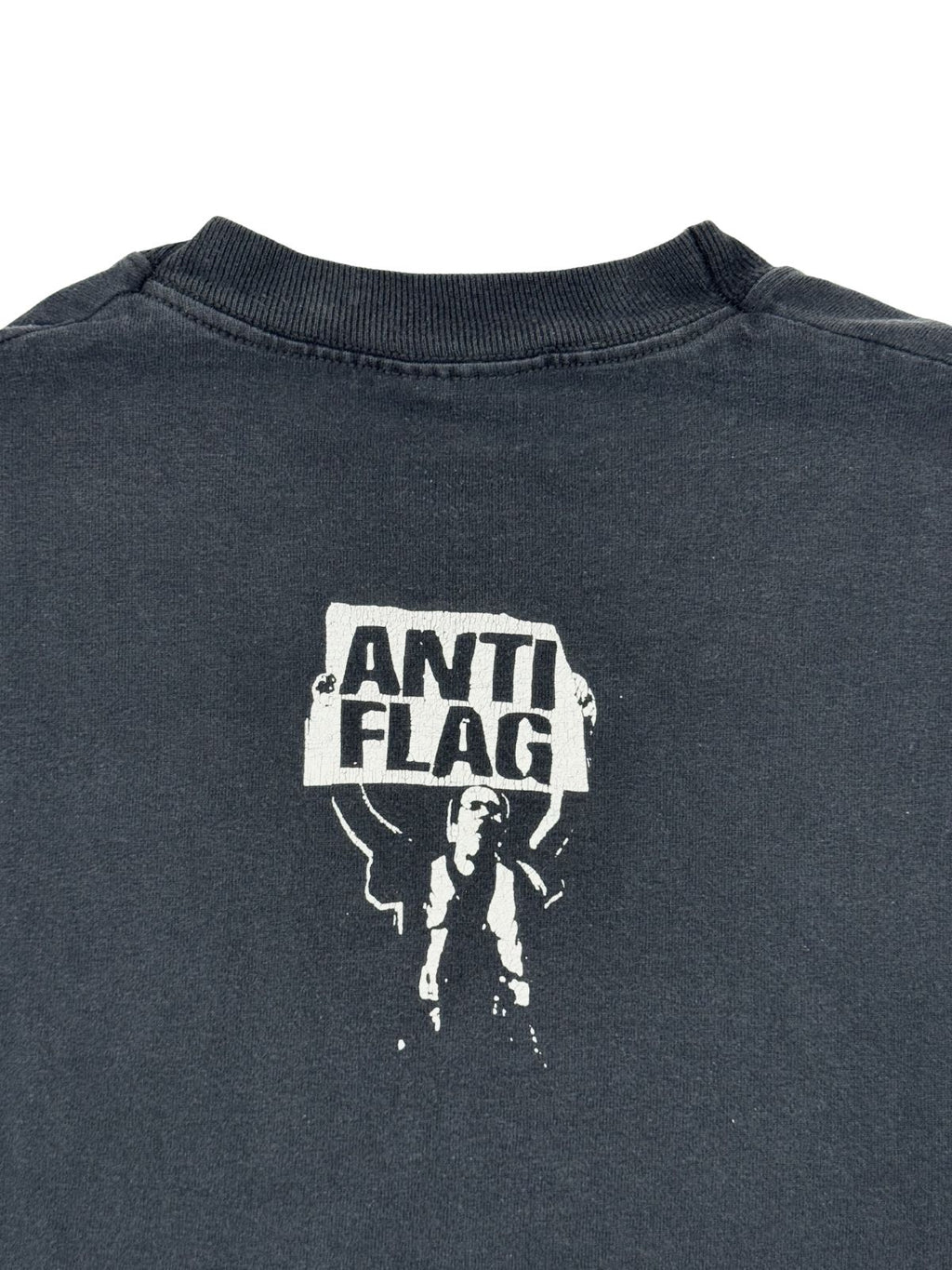 Vergrößerte Ansicht des „Anti-Flag“-Grafikprints im Nackenbereich; zeigt die Textur des weißen Siebdrucks auf verwaschenem Schwarz.