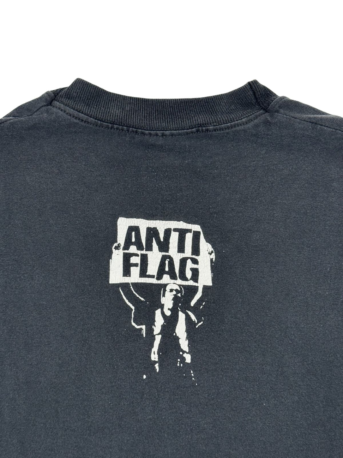 Vergrößerte Ansicht des „Anti-Flag“-Grafikprints im Nackenbereich; zeigt die Textur des weißen Siebdrucks auf verwaschenem Schwarz.