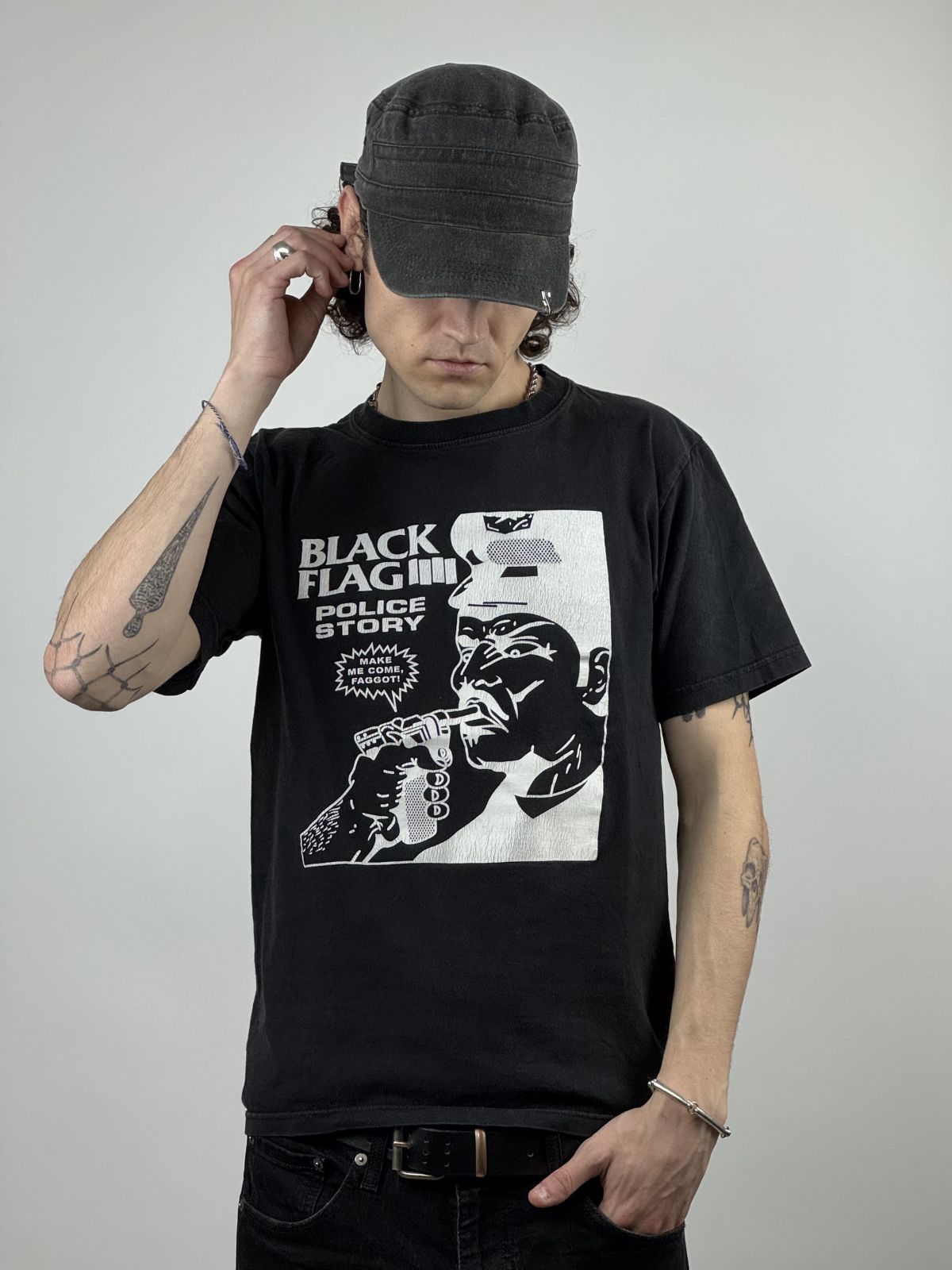 Ein Model trägt das Black Flag „Police Story“ Vintage Shirt; Fokus auf dem Grafikprint und dem lockeren Punk-Rock-Streetwear-Look.
