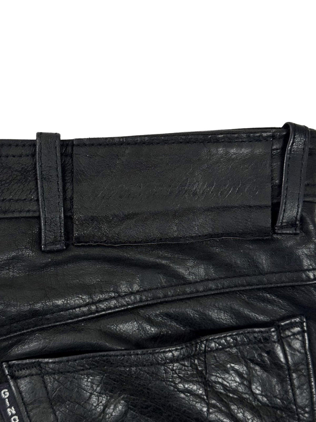 Geprägtes Leder-Patch der Marke Gino Ginero am hinteren Bund der schwarzen Vintage Echtlederhose.