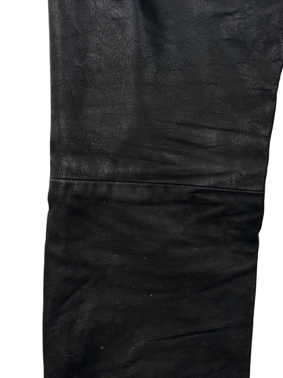 Detailaufnahme der horizontalen Knienaht und der Narbenstruktur des schwarzen Echtleders bei einer Vintage Bikerhose.