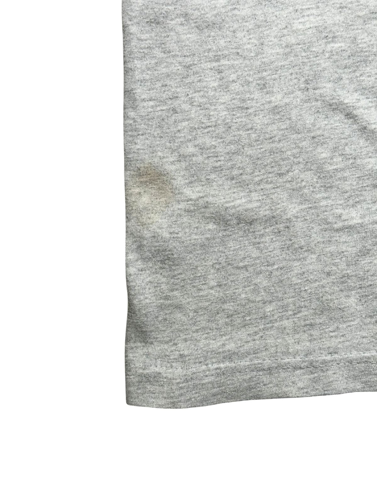Nahaufnahme des unteren vorderen Saums mit Doppelnaht, die eine leichte, bräunliche Verfärbung auf der linken Seite des Shirts zeigt.