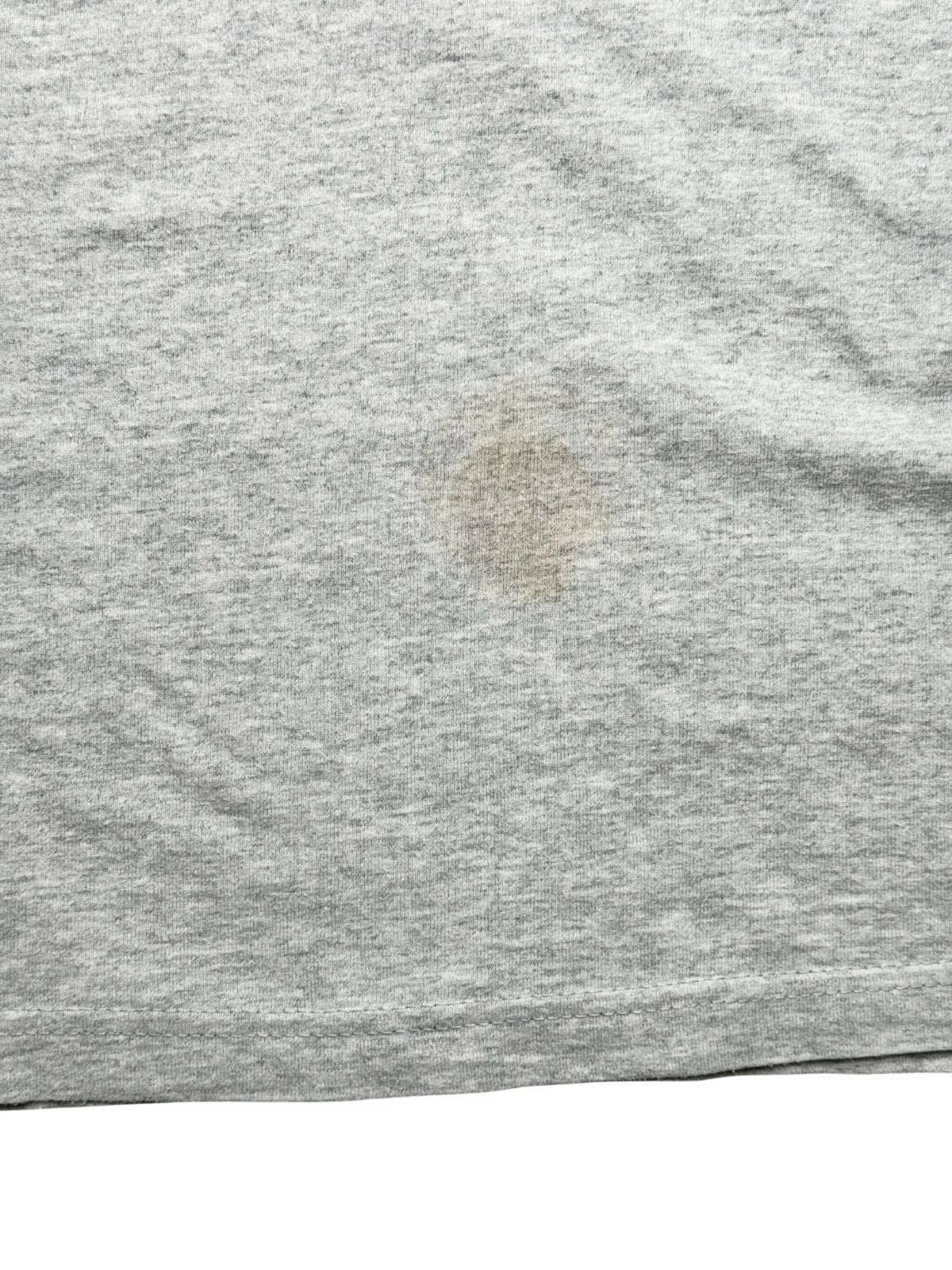 Detailaufnahme der unteren Vorderseite mit einem deutlich sichtbaren, kreisrunden Flecken (Stain) auf dem grauen Baumwollmaterial.