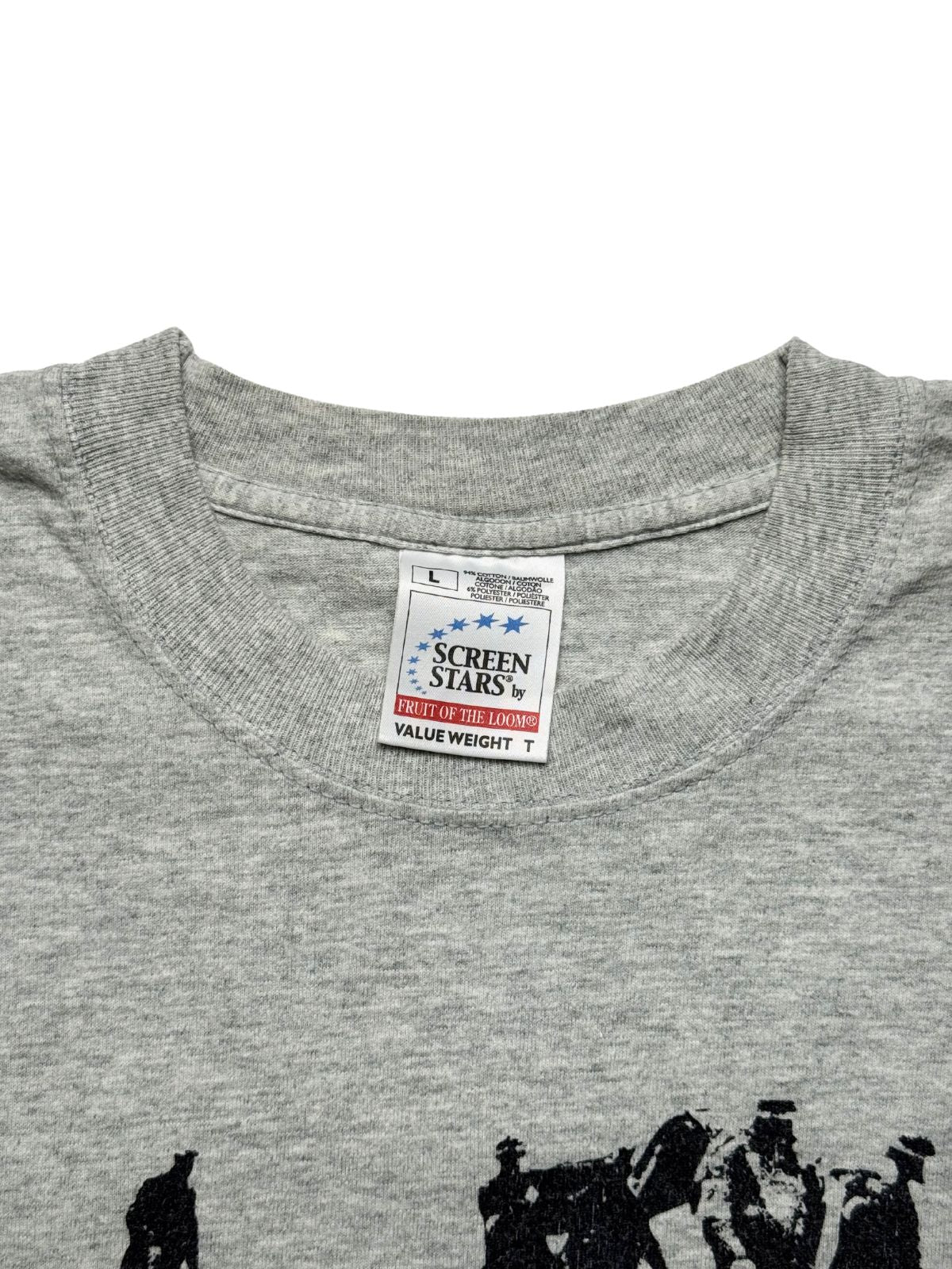 Nahaufnahme des inneren Kragenbereichs des graumelierten Boysetsfire Shirts mit einem originalen, weißen Nackenetikett der Marke „Screen Stars by Fruit of the Loom (Value Weight)“ in Größe L.