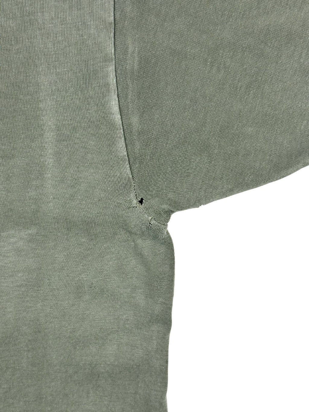 Nahaufnahme eines kleinen Lochs (Pinhole) an der hinteren rechten Achselnaht des 80er-Jahre Militär-Shirts.