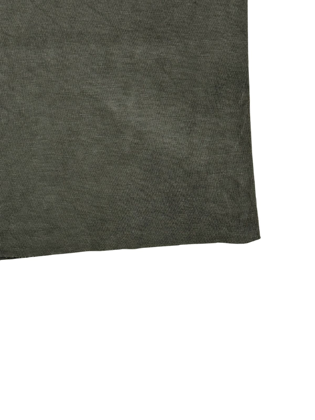 Detailaufnahme des abgeschnittenen, offenen Saums (Raw Hem) am olivgrünen Vintage-Militär-Shirt.