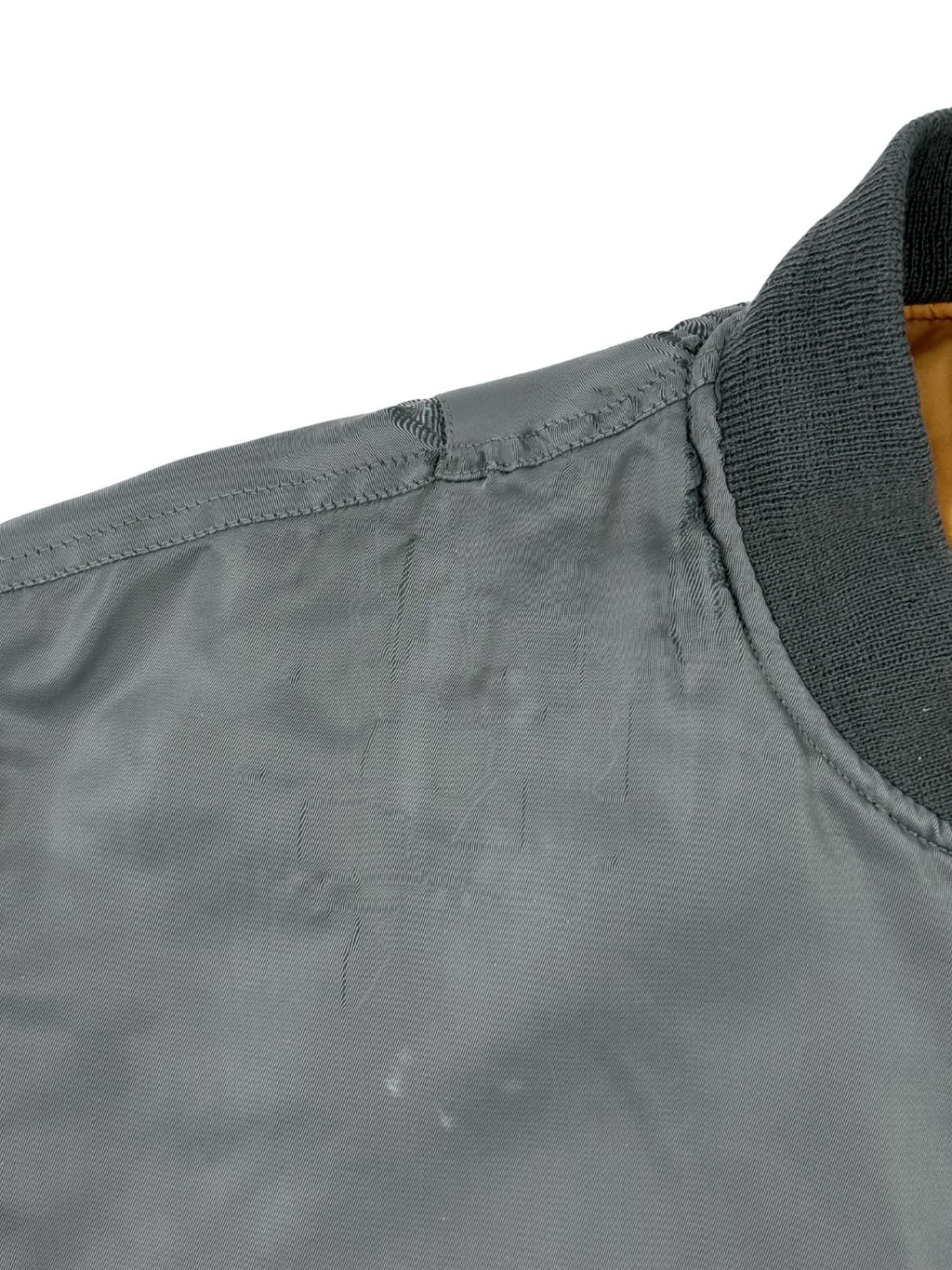 Nahaufnahme der rechten vorderen Schulterpartie zur Zustandsprüfung. Zu sehen sind Abnutzungen im Nylon-Material in Form von gezogenen Fäden und leichten, hellen Flecken.