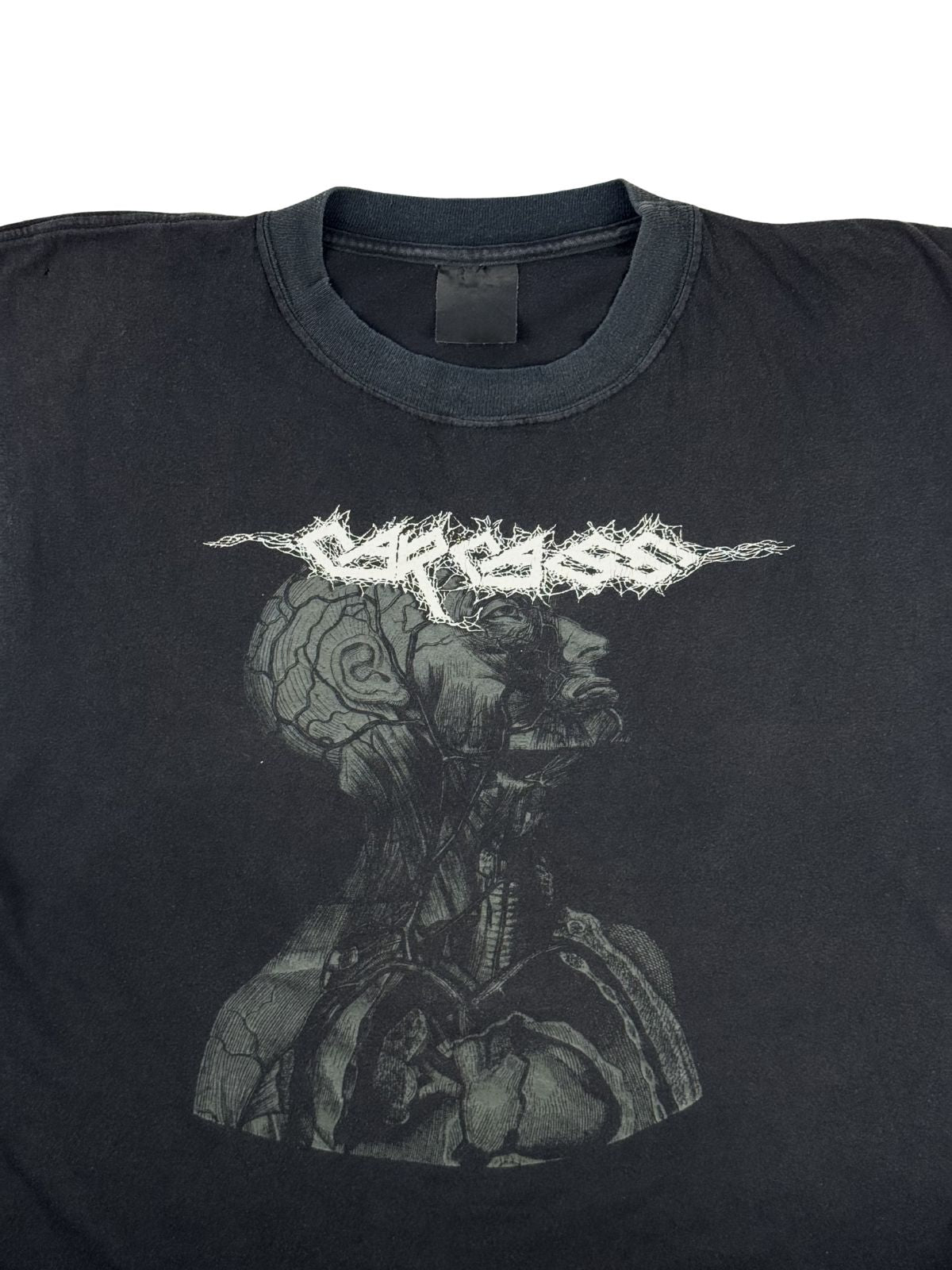 Detailansicht der Vorderseite des Carcass Shirts mit Fokus auf den Rundhalsausschnitt und das detaillierte Artwork des medizinischen Kopfschnitts unter dem gezackten Bandlogo.