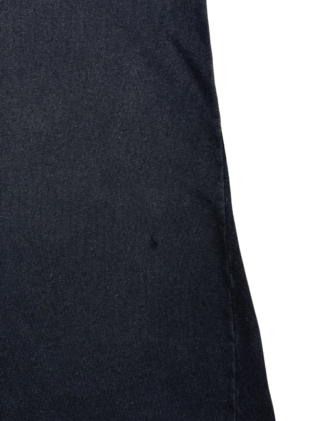Detailaufnahme der Stoffoberfläche mit einem kleinen, authentischen Loch (Pinhole) im schwarzen Baumwollmaterial.