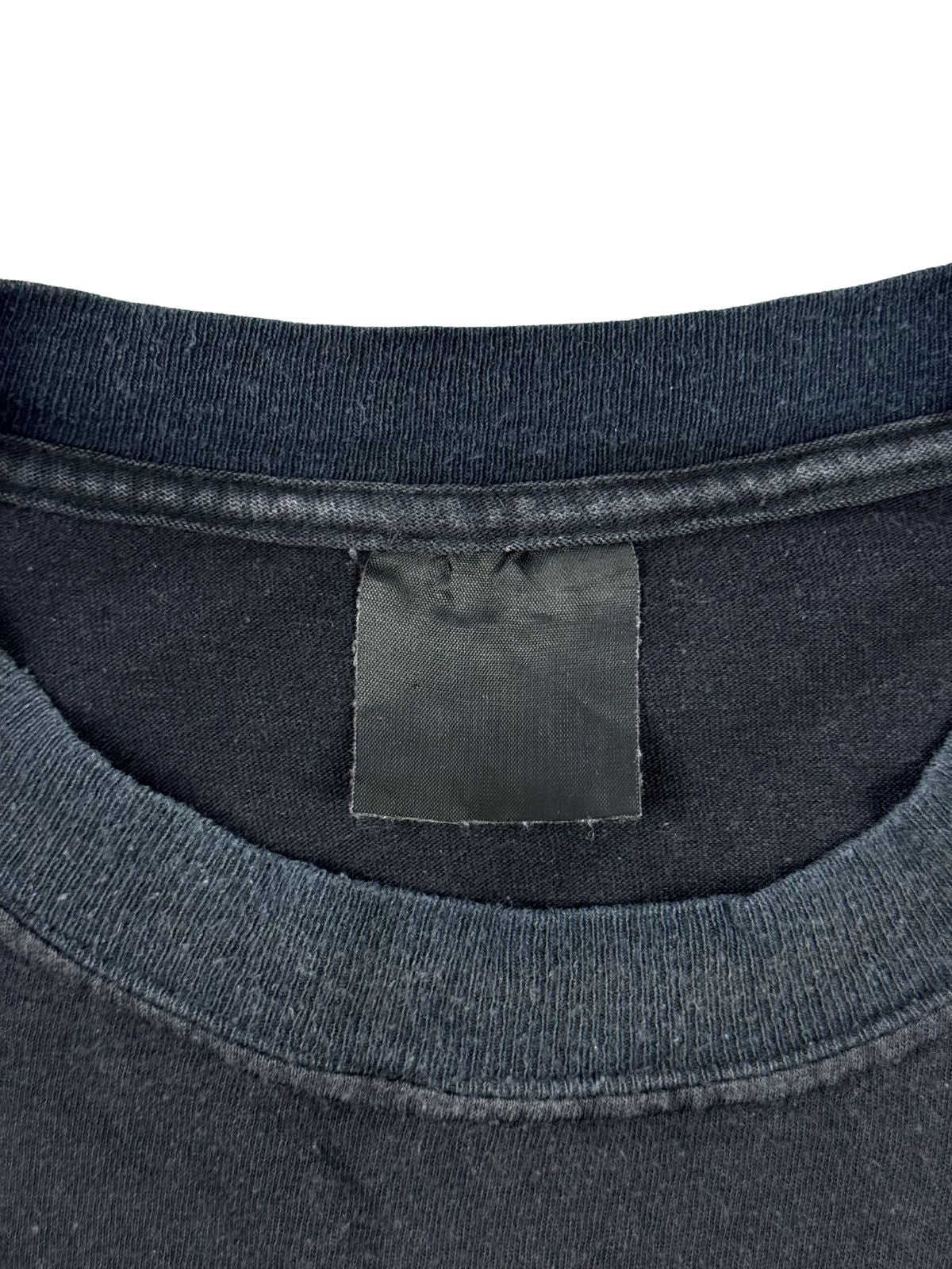 Nahaufnahme des inneren Kragenbereichs mit einem komplett verwaschenen, schwarzen Stoffetikett ohne sichtbaren Aufdruck (Blank Tag).