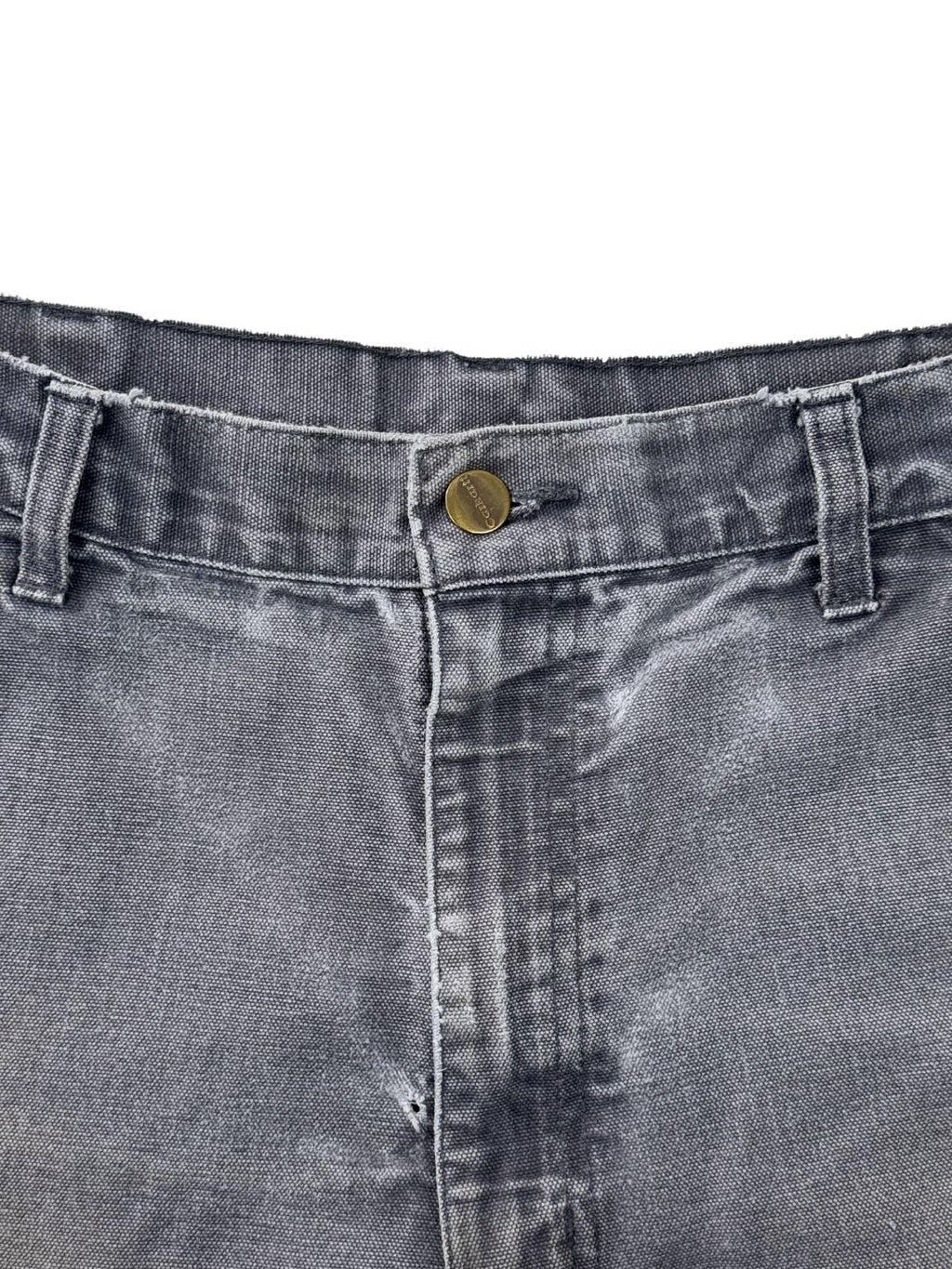 Nahaufnahme des metallischen Carhartt-Logoknopfs am Bund einer grauen Vintage Arbeitshose.