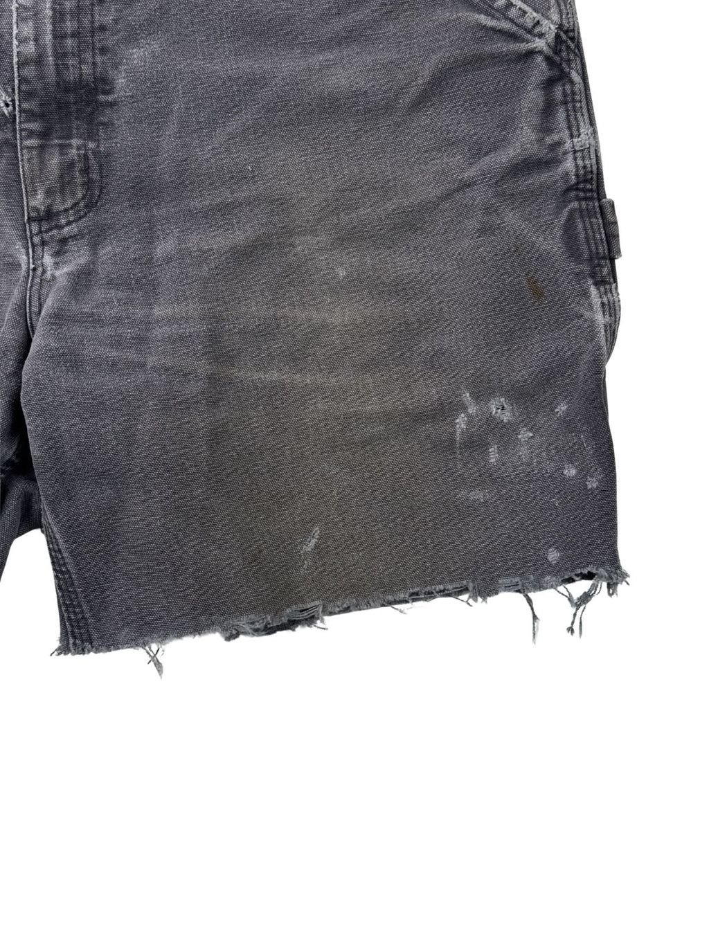 Authentische Flecken und Farbspritzer auf dem grauen Canvas-Stoff einer Vintage Carhartt Shorts (linke Vorderseite).