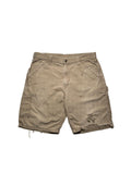 Originale Vintage Carhartt Carpenter Shorts aus festem Canvas-Stoff in ausgewaschenem Beige. Frontansicht der Workwear-Hose mit authentischen Farbspritzern und einem thrashed Loch am linken Hosenbein.