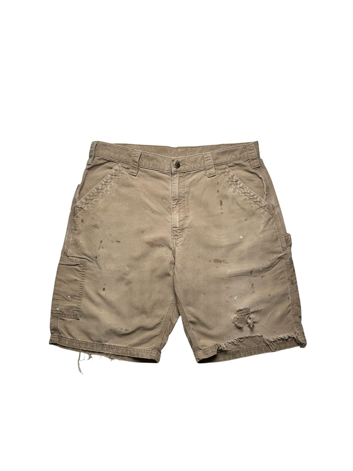 Originale Vintage Carhartt Carpenter Shorts aus festem Canvas-Stoff in ausgewaschenem Beige. Frontansicht der Workwear-Hose mit authentischen Farbspritzern und einem thrashed Loch am linken Hosenbein.