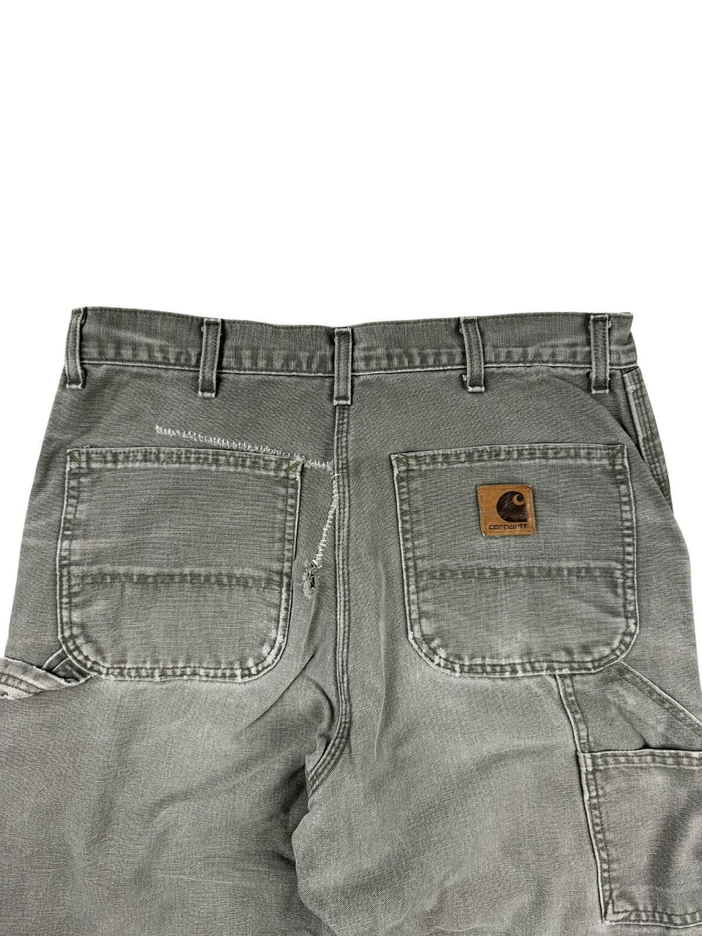 Detailaufnahme der hinteren Hüftpartie mit den beiden Gesäßtaschen. Die linke Tasche zeigt eine grob von Hand geflickte, weiße Reparatur-Mend-Naht an der oberen Kante und der Seitennaht.