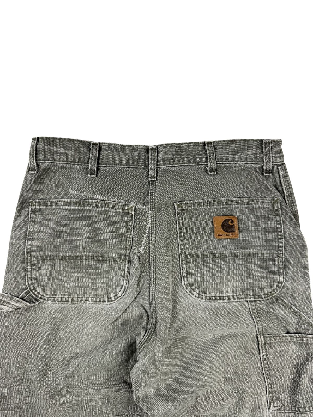 Detailaufnahme der hinteren Hüftpartie mit den beiden Gesäßtaschen. Die linke Tasche zeigt eine grob von Hand geflickte, weiße Reparatur-Mend-Naht an der oberen Kante und der Seitennaht.