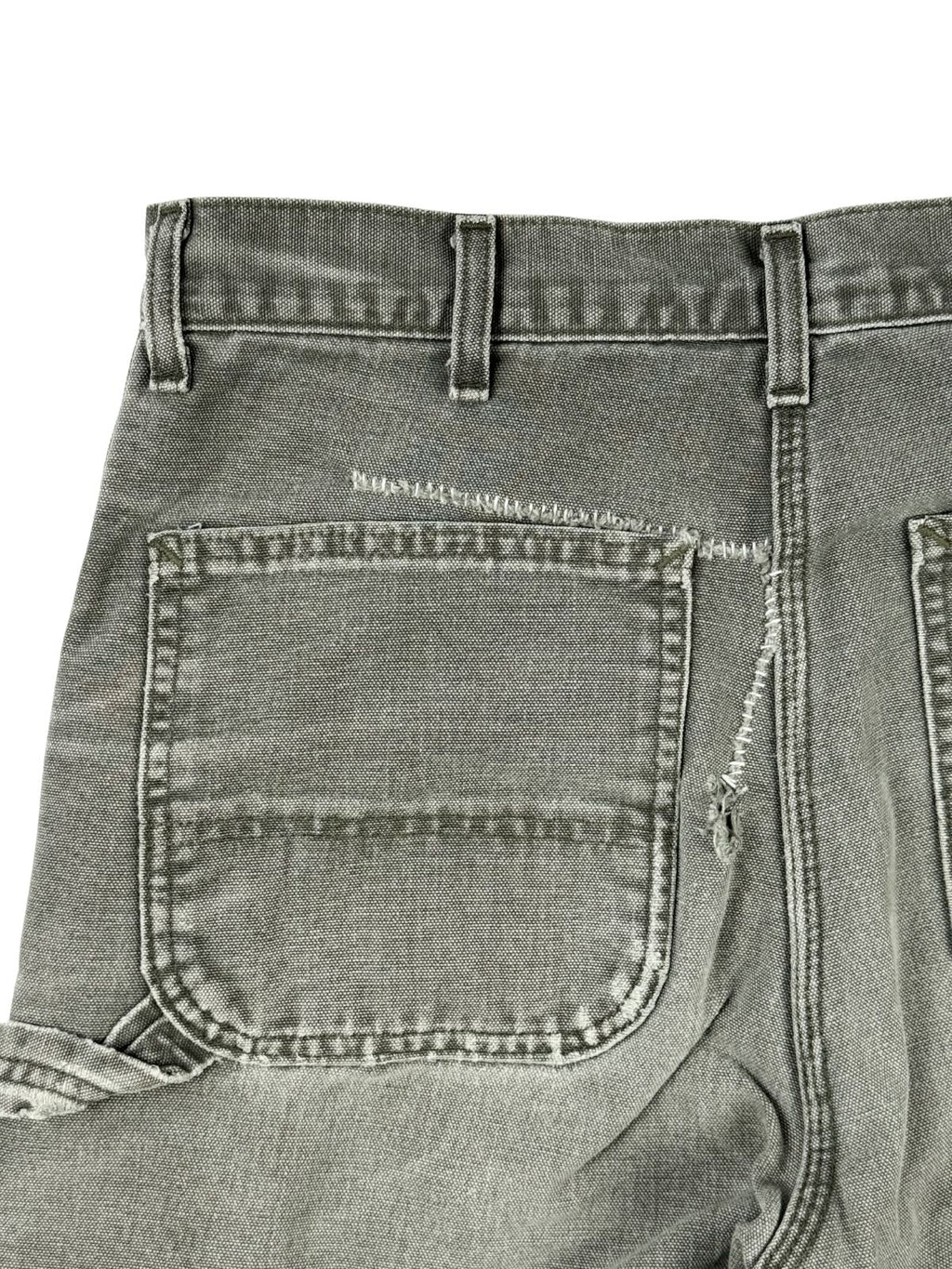 Detaillierter Ausschnitt der linken Gesäßtasche mit Fokus auf den thrashed Look und die auffällige, weiße Stopfnaht (Hand-Repair), die einen langen Riss im Stoff schließt.
