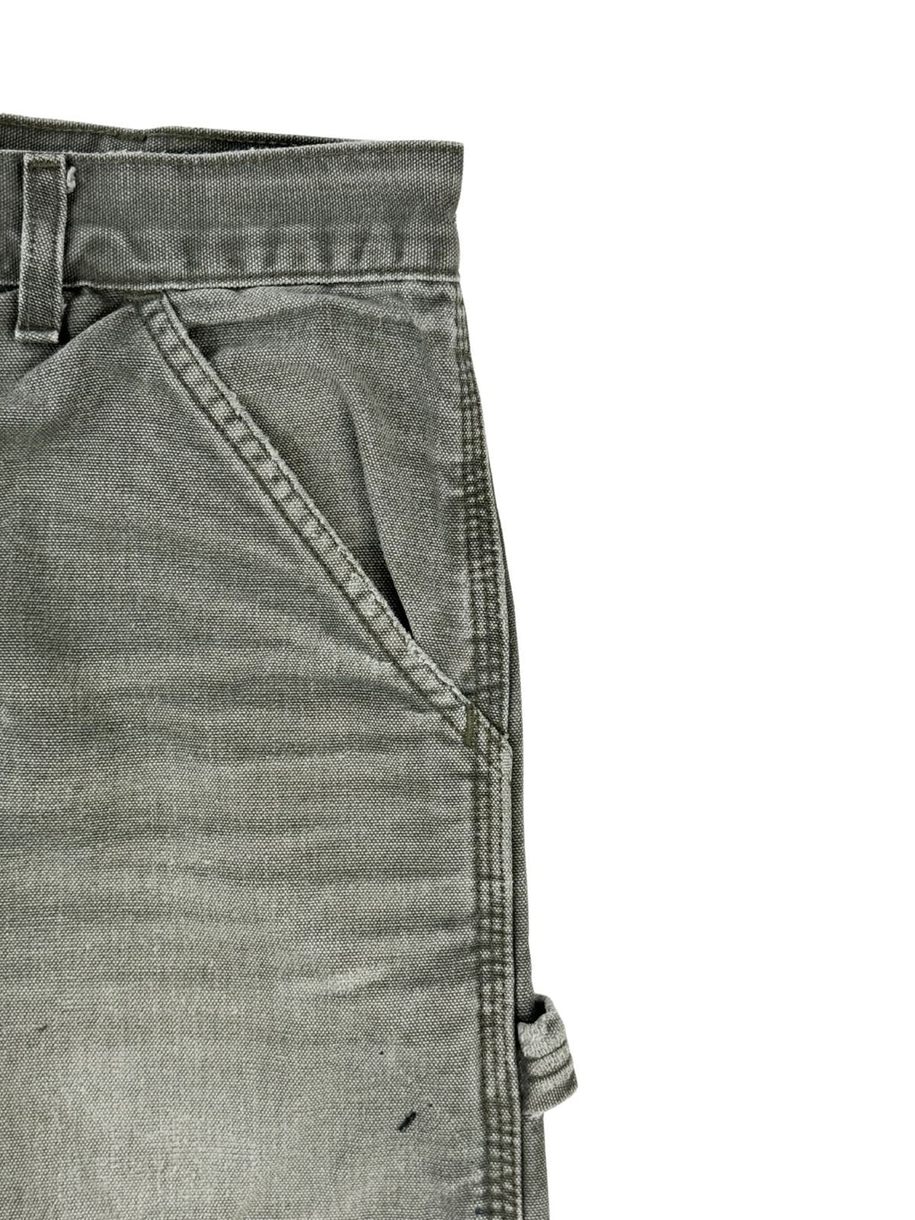 Detailansicht der linken vorderen Eingriffstasche der grauen Carhartt-Hose mit dreifach vernähten Hauptnähten (Triple-Stitched Seams) und sichtbaren Waschspuren am Bund.