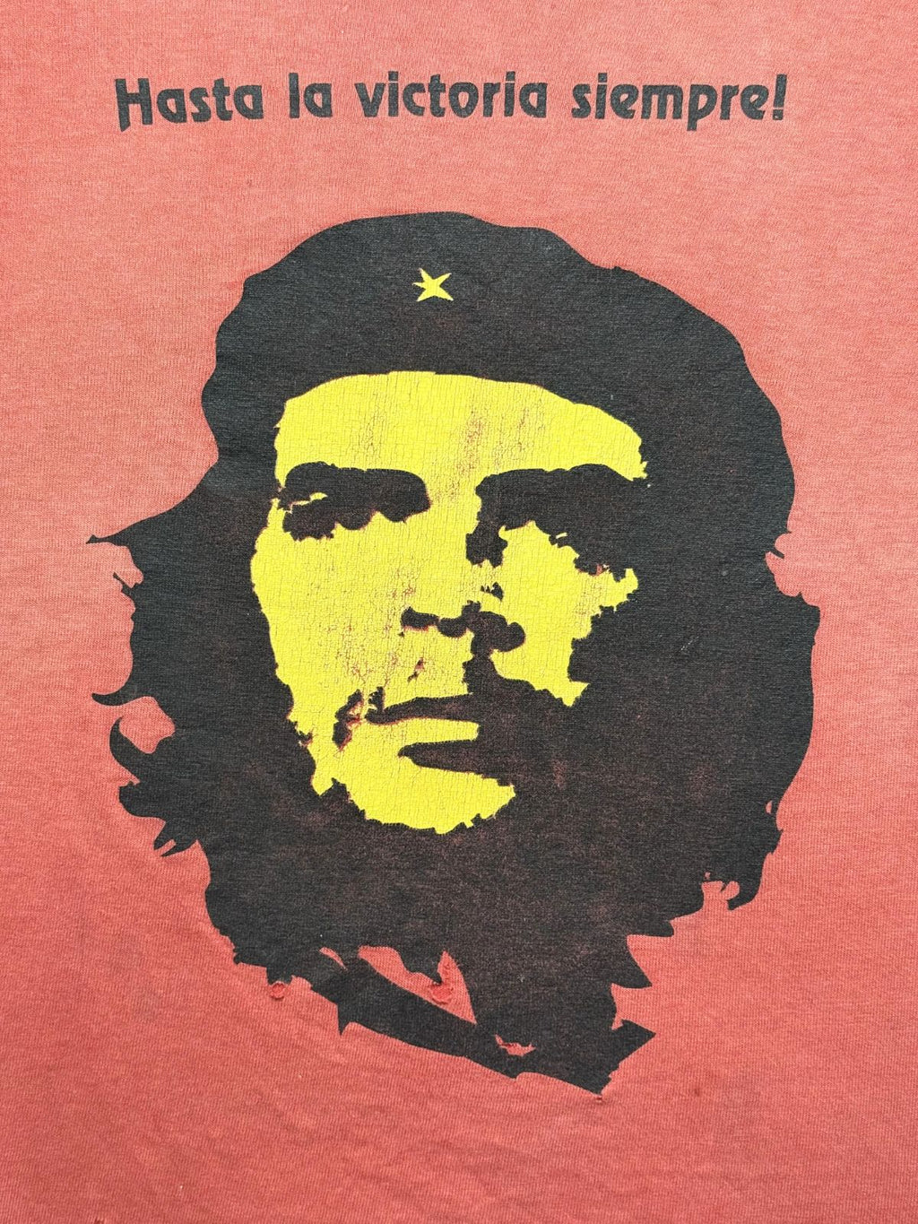 Detailansicht des vorderen Siebdrucks mit dem berühmten Porträt von Che Guevara mit Baret, gelbem Gesicht, schwarzem Haar und dem spanischen Slogan „Hasta la victoria siempre!“.