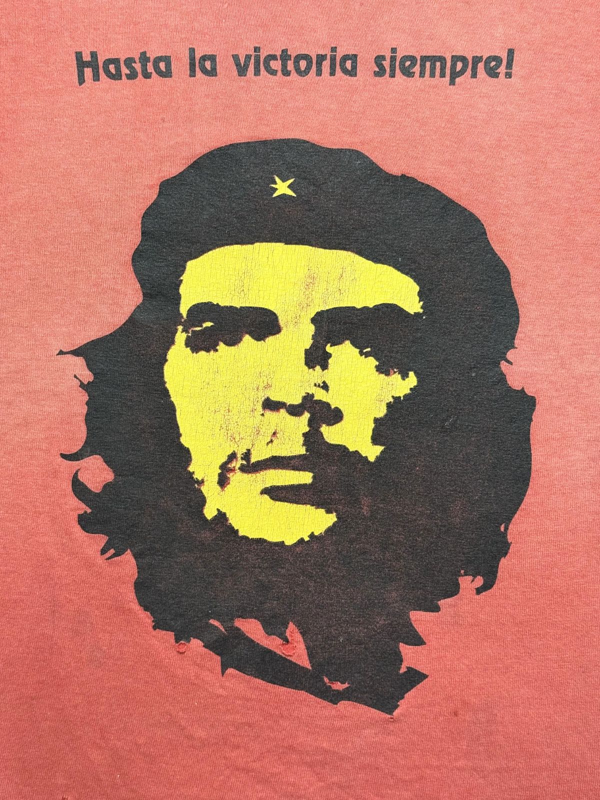 Detailansicht des vorderen Siebdrucks mit dem berühmten Porträt von Che Guevara mit Baret, gelbem Gesicht, schwarzem Haar und dem spanischen Slogan „Hasta la victoria siempre!“.