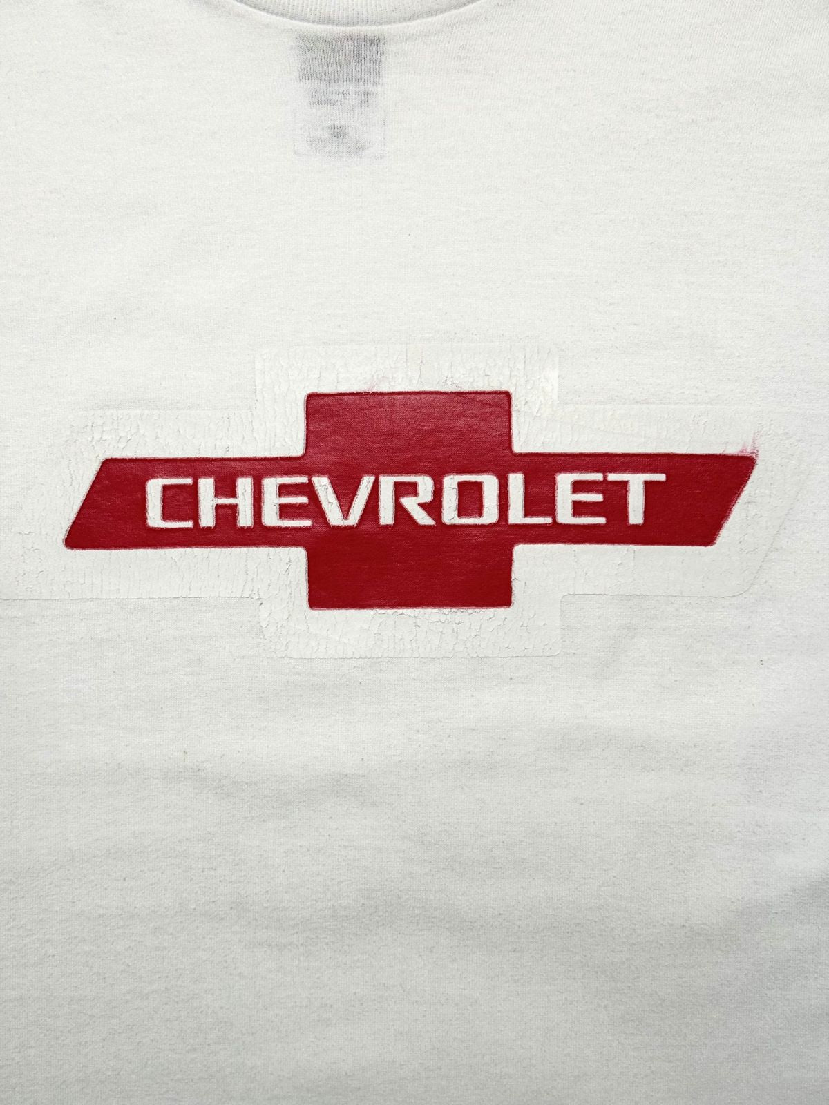 Detailansicht des vorderen Siebdrucks mit dem roten Chevrolet-Kreuz-Logo und dem weißen Markenschriftzug im gealterten Used-Look.