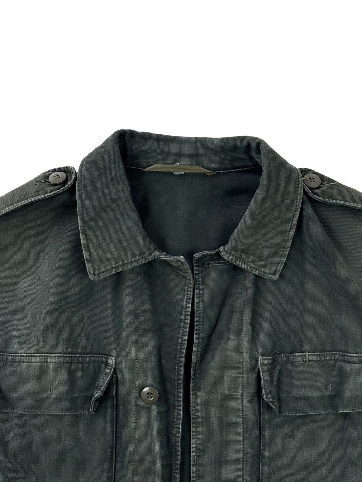 Nahaufnahme des oberen Frontbereichs der schwarzen Vintage-Militärjacke. Zu sehen sind der klassische Kragen, die Knopfleiste, Schulterklappen sowie zwei Brusttaschen mit Klappen.
