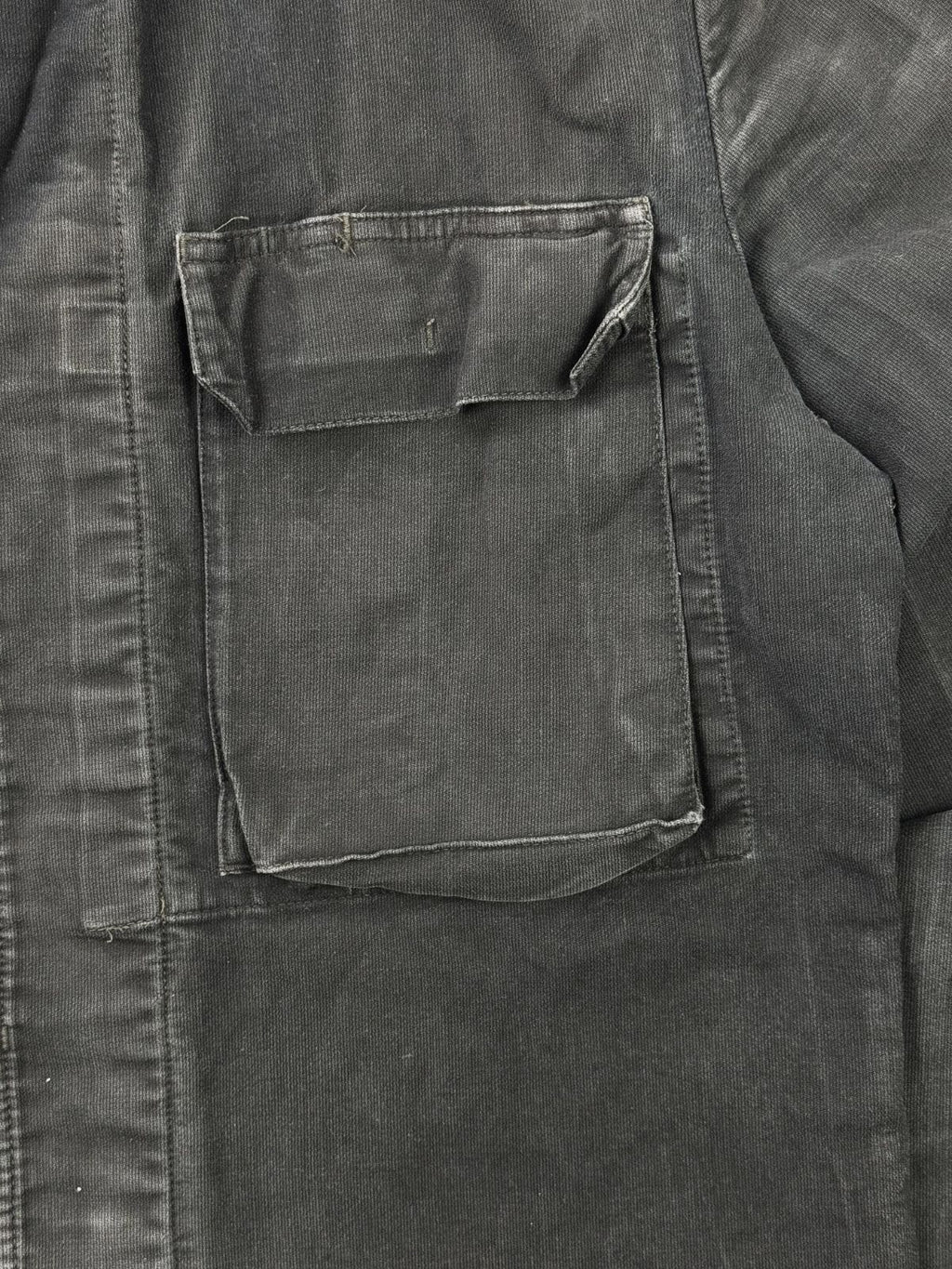 Detailansicht der aufgesetzten linken Brusttasche mit verdecktem Knopfverschluss auf dem robusten, schwarzen Baumwoll-Moleskin-Stoff.