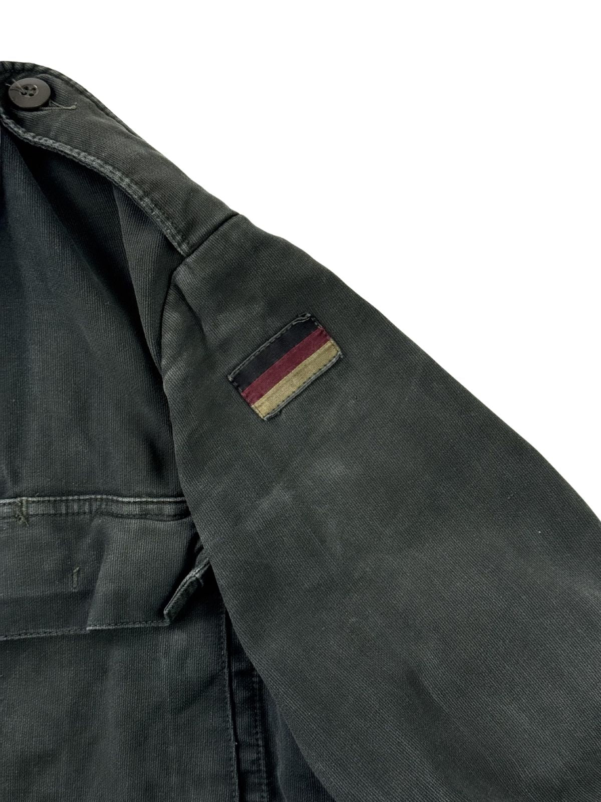Nahaufnahme des linken Oberärmels mit dem originalen, stark verwaschenen und ausgeblichenen schwarz-rot-goldenen Flaggen-Patch der Bundeswehr.