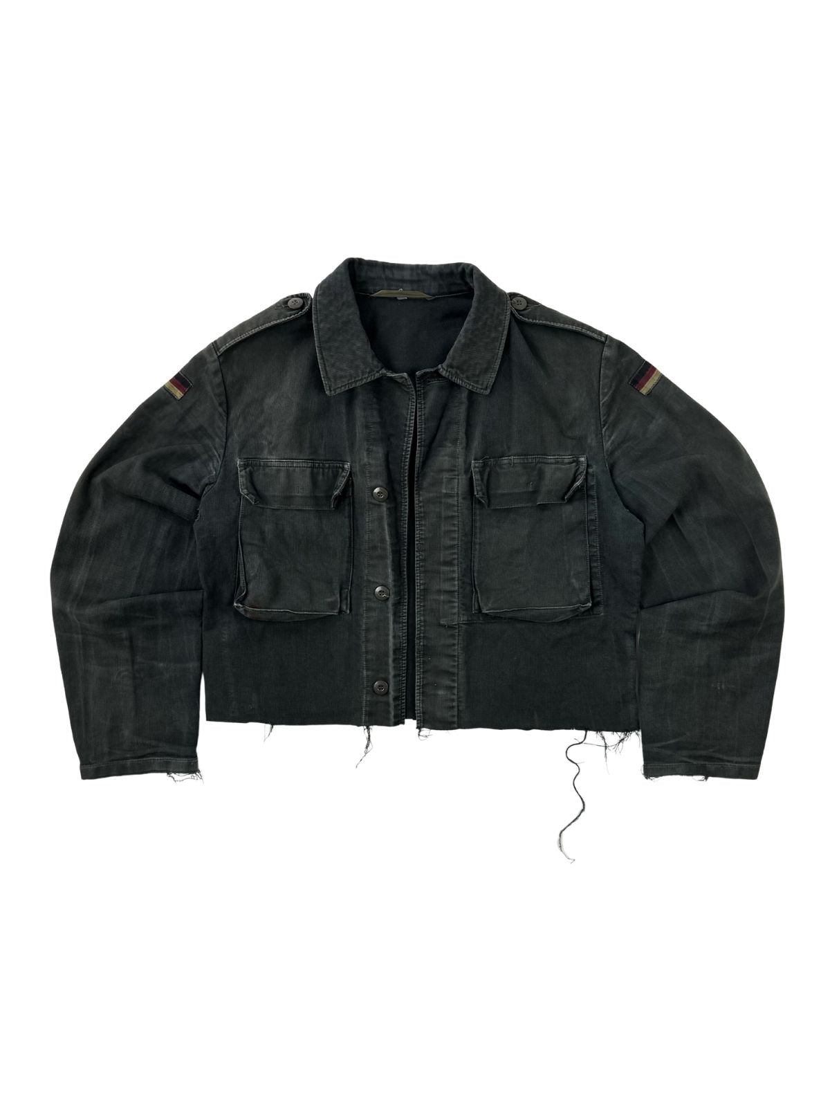 Komplettansicht der Vorderseite einer umgearbeiteten (cropped) Vintage Bundeswehr Feldjacke aus den 1980er Jahren in verwaschenem Schwarz. Die Moleskin-Jacke hat zwei große Brusttaschen, Schulterklappen, Flaggen-Patches auf den Ärmeln und einen kurz abgeschnittenen, ausgefransten Saum. Flatlay auf weißem Hintergrund.