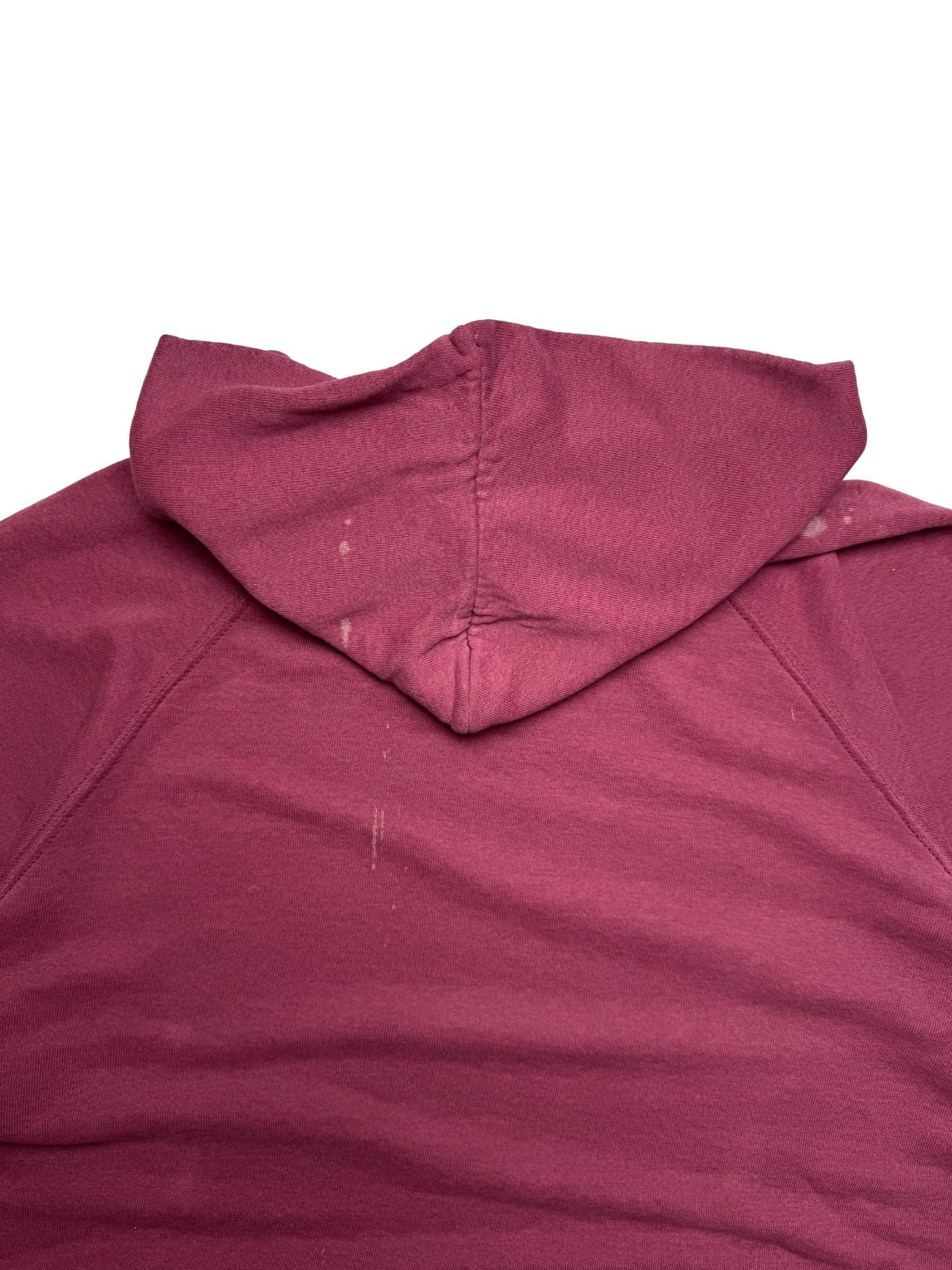 Nahaufnahme der oberen Rückseite mit der spitz zulaufenden Kapuze und leicht hellen Flecken im bordeauxroten Sweatstoff.