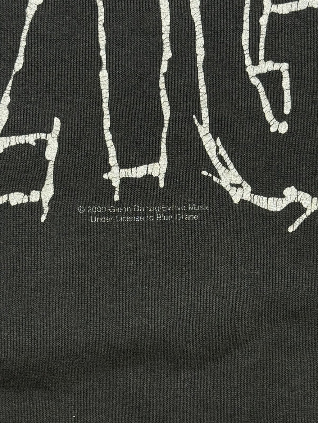 Makroaufnahme des Lizenzaufdrucks unter dem Frontprint: „© 2000 Glenn Danzig's Evilive Music. Under License to Blue Grape“.