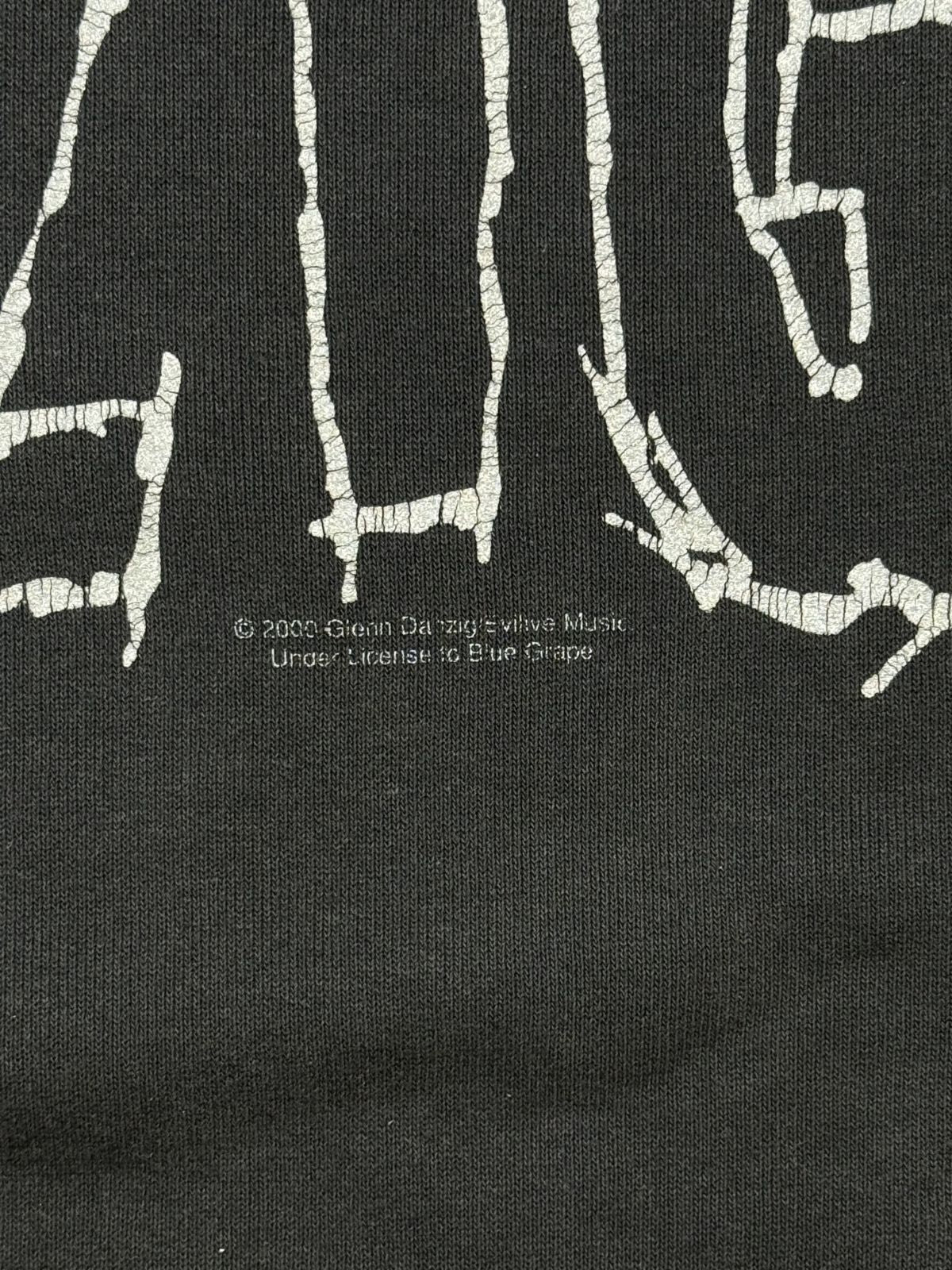Makroaufnahme des Lizenzaufdrucks unter dem Frontprint: „© 2000 Glenn Danzig's Evilive Music. Under License to Blue Grape“.