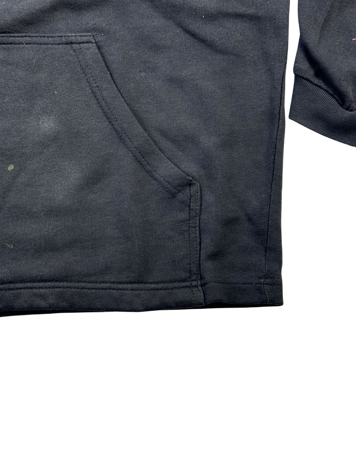 Detailansicht der unteren linken Saumkante und Kängurutasche des schwarzen Hoodies.