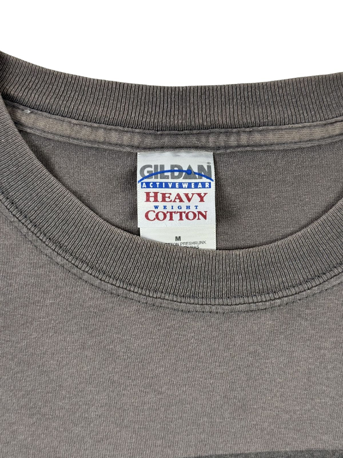Nahaufnahme des originalen „Gildan Activewear Heavy Cotton“ Kragenetiketts in Größe M, ein wichtiges Merkmal für die Datierung des 2007er Merch-Artikels.