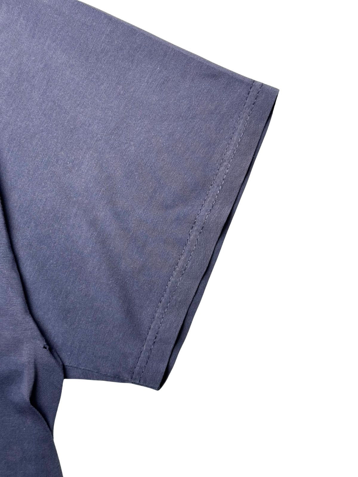 Detailansicht des kurzen Ärmelbunds mit doppelter Verarbeitungsnaht auf blau-violettem Baumwollstoff.