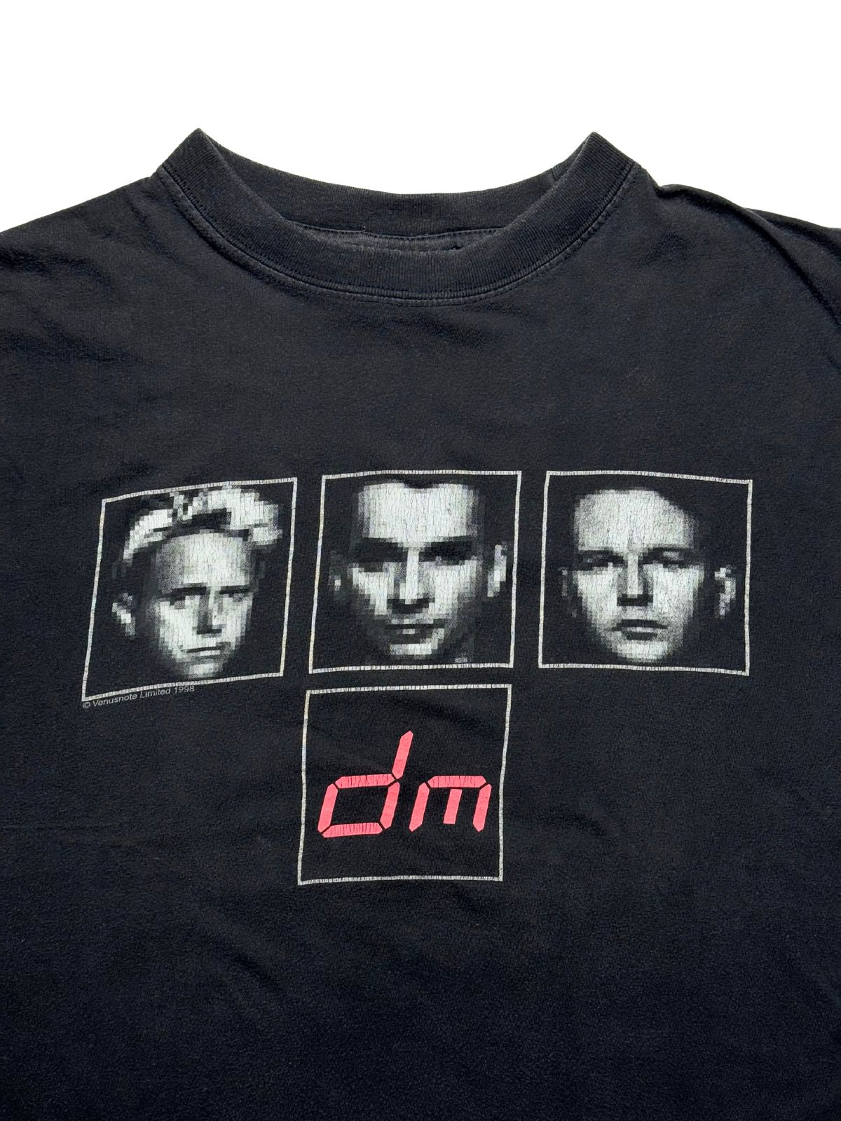 Detailansicht der vorderen Brustpartie mit Blick auf den gerippten Rundhalsausschnitt, die drei gepixelten Band-Porträts (Martin Gore, Dave Gahan, Andrew Fletcher) und das pinke „dm“-Digital-Logo.