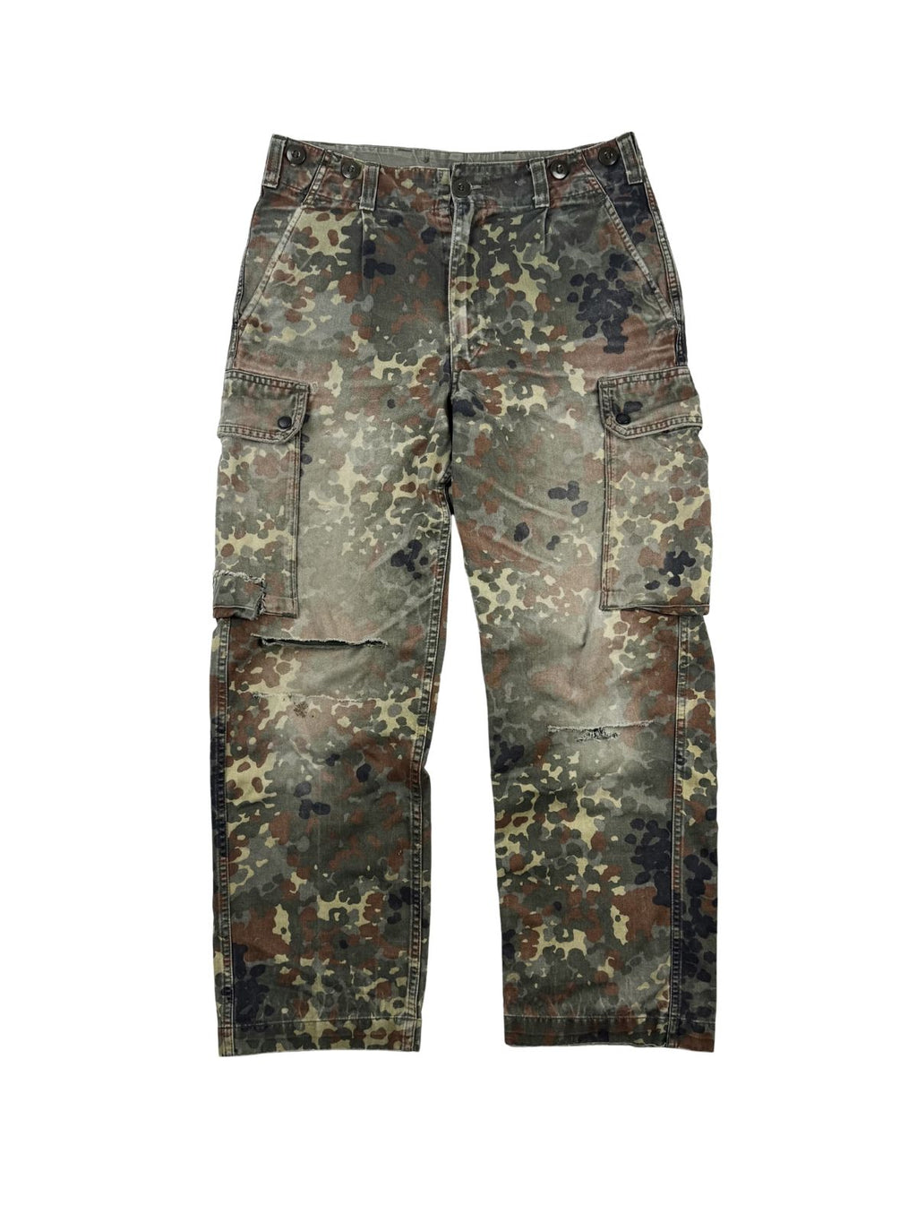 Komplettansicht der Vorderseite einer verwaschenen Vintage Bundeswehr Cargo-Feldhose im Flecktarn-Muster aus dem Jahr 1997. Die Militärhose besitzt zwei große, aufgesetzte Beintaschen und zeigt markante Risse im Kniebereich für einen authentischen Grunge- und Distressed-Look. Flatlay auf weißem Hintergrund.