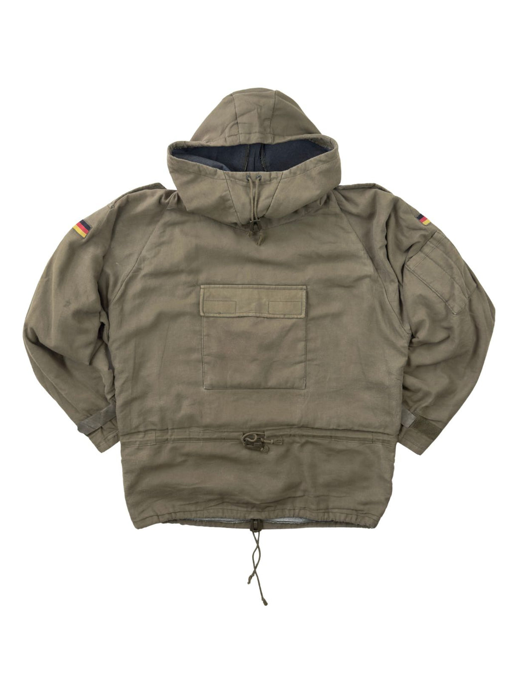 Komplettansicht der Vorderseite eines olivgrünen Vintage Bundeswehr Militär-Smocks aus den 1980er Jahren. Der Schlupfanorak (Windbreaker) verfügt über eine große Kängurutasche auf der Brust, Kordelzüge an Taille und Saum sowie Deutschland-Patches auf den Ärmeln. Flatlay auf weißem Hintergrund.